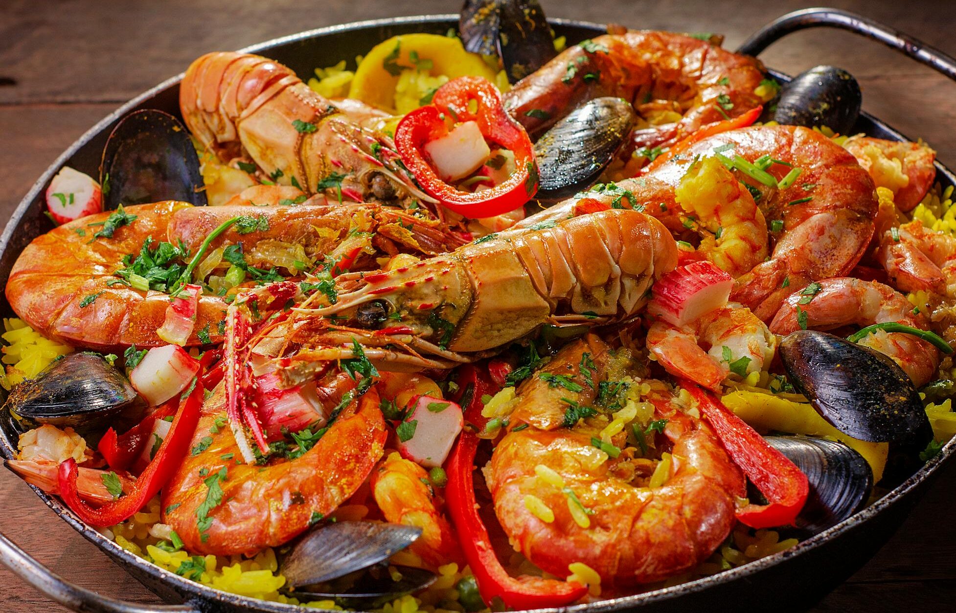 A vibrant and flavorful seafood paella served in a pan with mussels and shrimp.