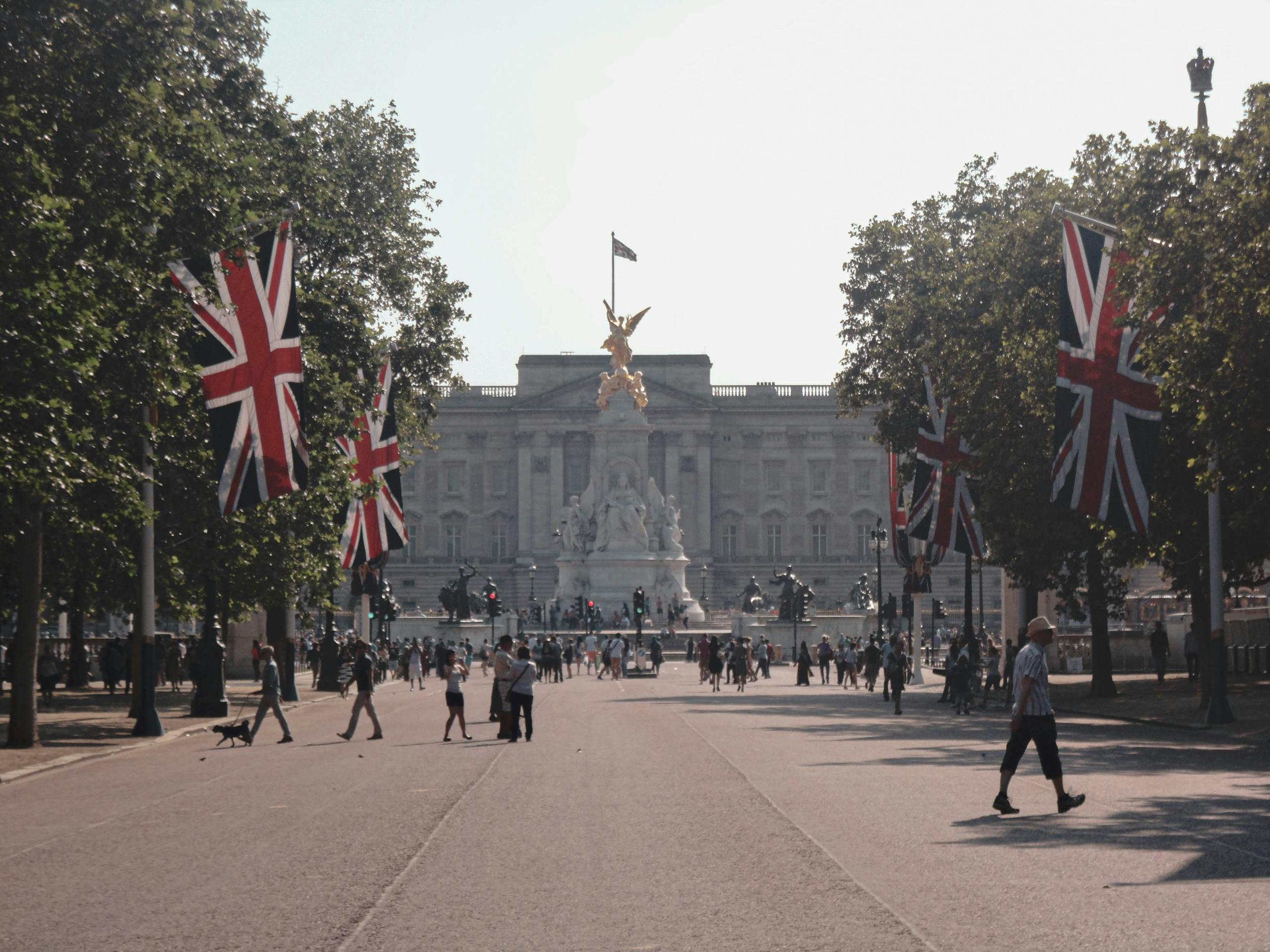A vibrant day at Buckingham Palace with Union Jack flags and tourists exploring.