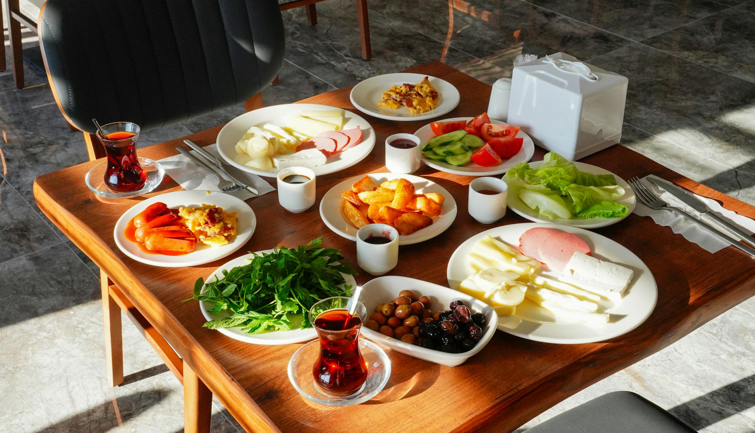 A vibrant traditional Turkish breakfast spread with tea, cheese, and fresh vegetables in Niğde, T&uuml;rkiye.