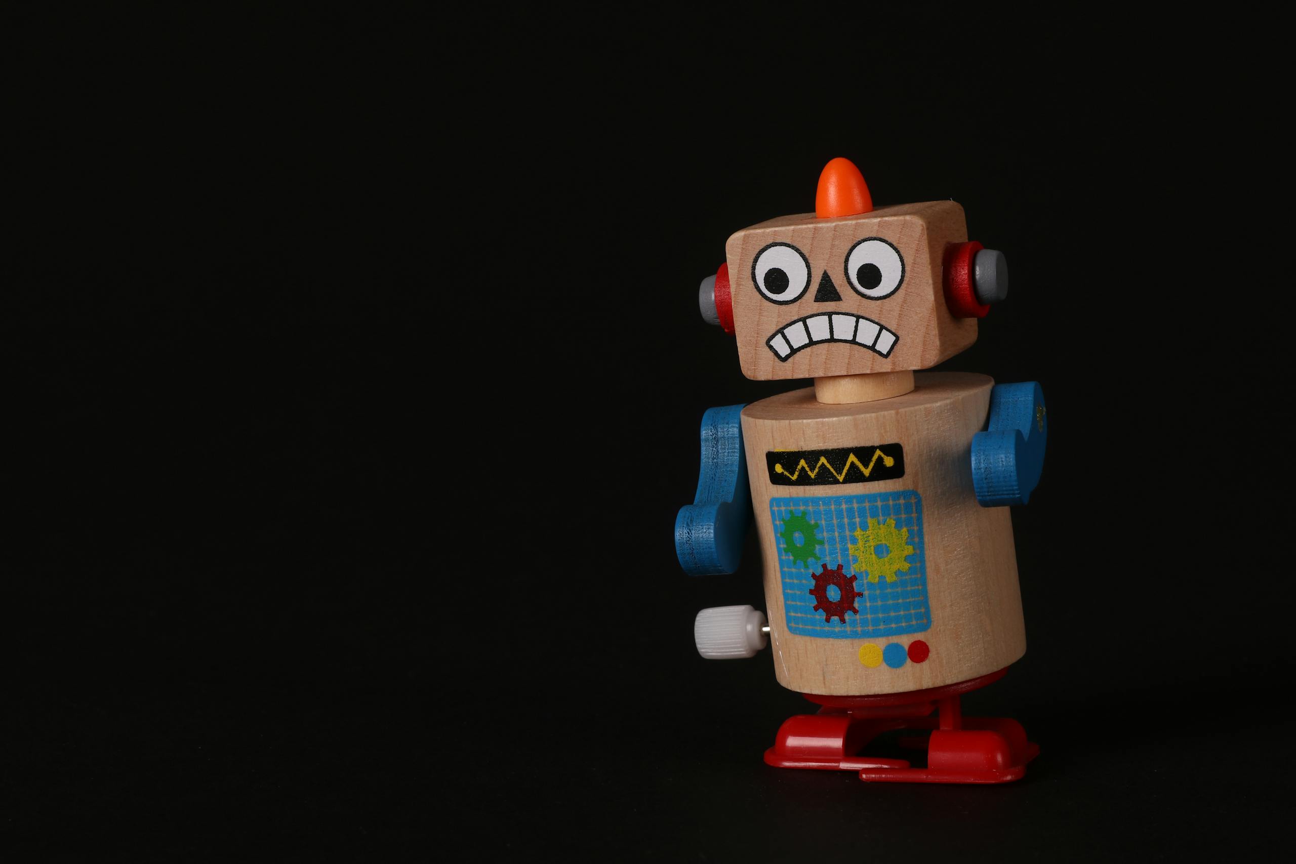 A vibrant wooden toy robot stands on a dark surface, showcasing vivid colors and playful design.