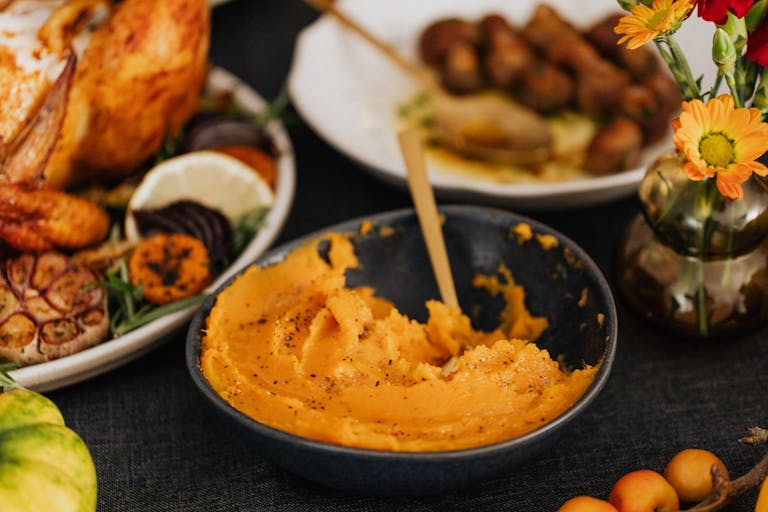 A warm and inviting spread of Thanksgiving dishes featuring roast turkey and mashed sweet potatoes.