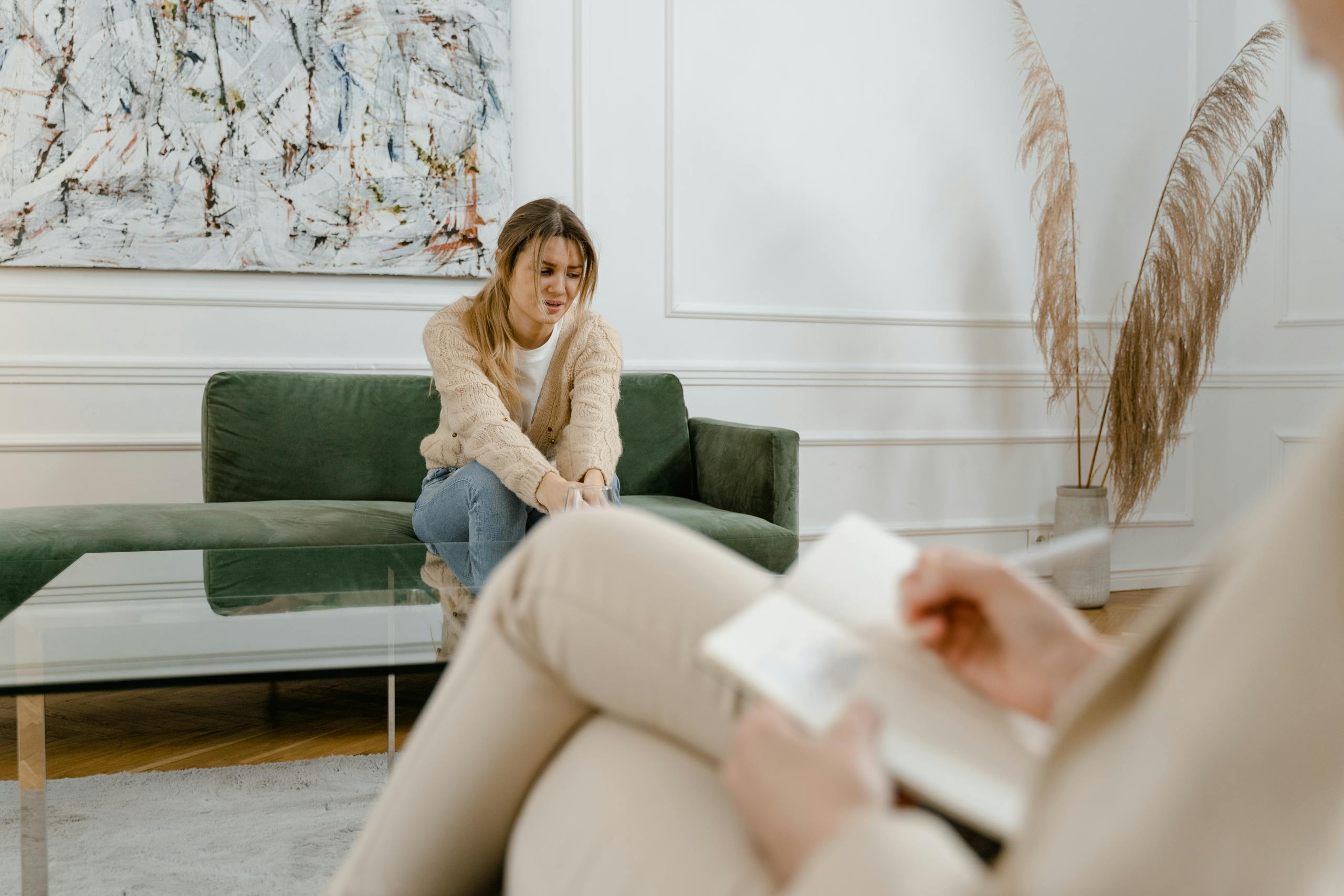 A woman during a therapy session in a modern living room setting, expressing concern.