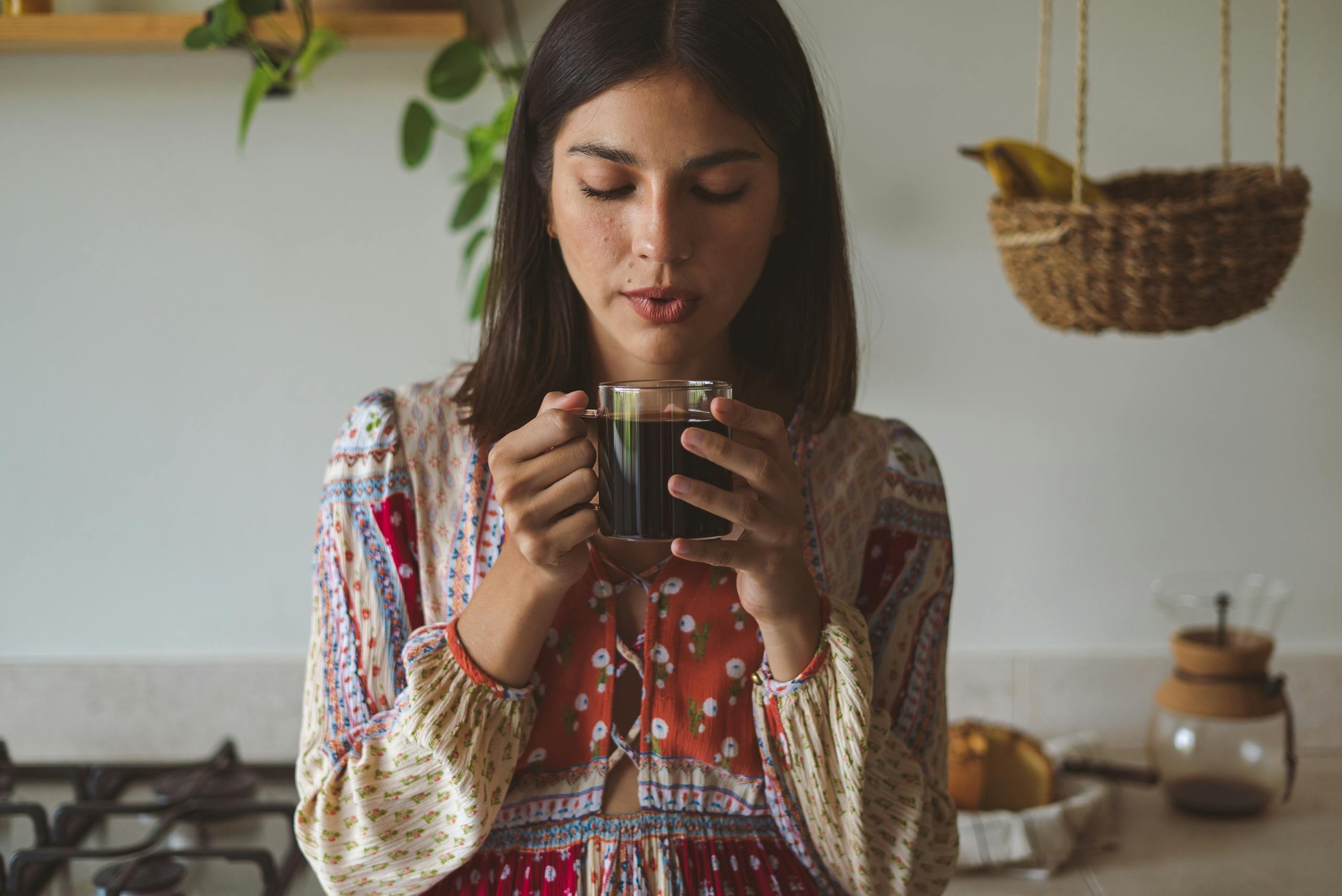 A woman enjoying a hot cup of coffee in a cozy kitchen environment, surrounded by natural elements.