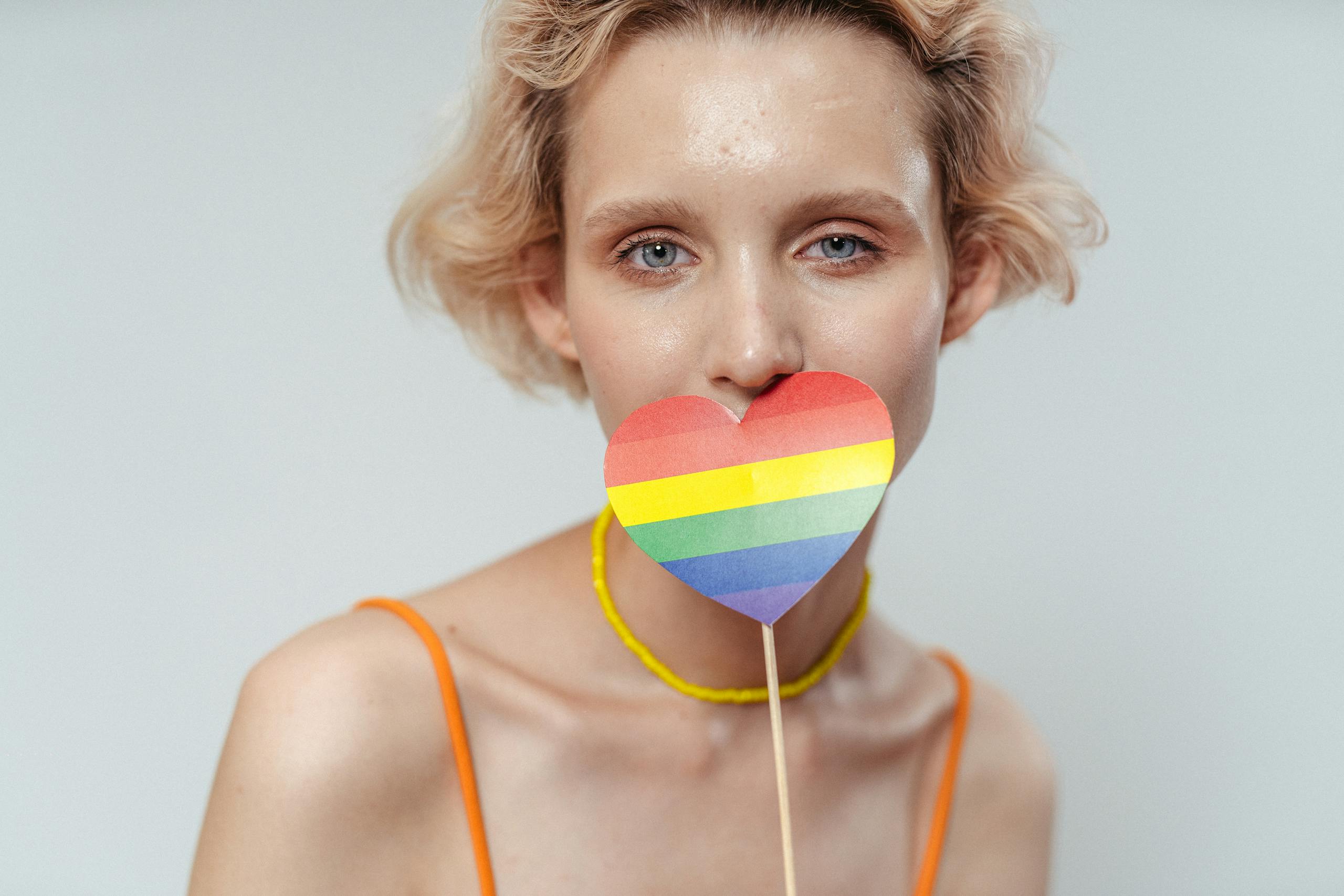 A woman holds a heart-shaped rainbow representing LGBT pride, creating an inclusive and vibrant image.