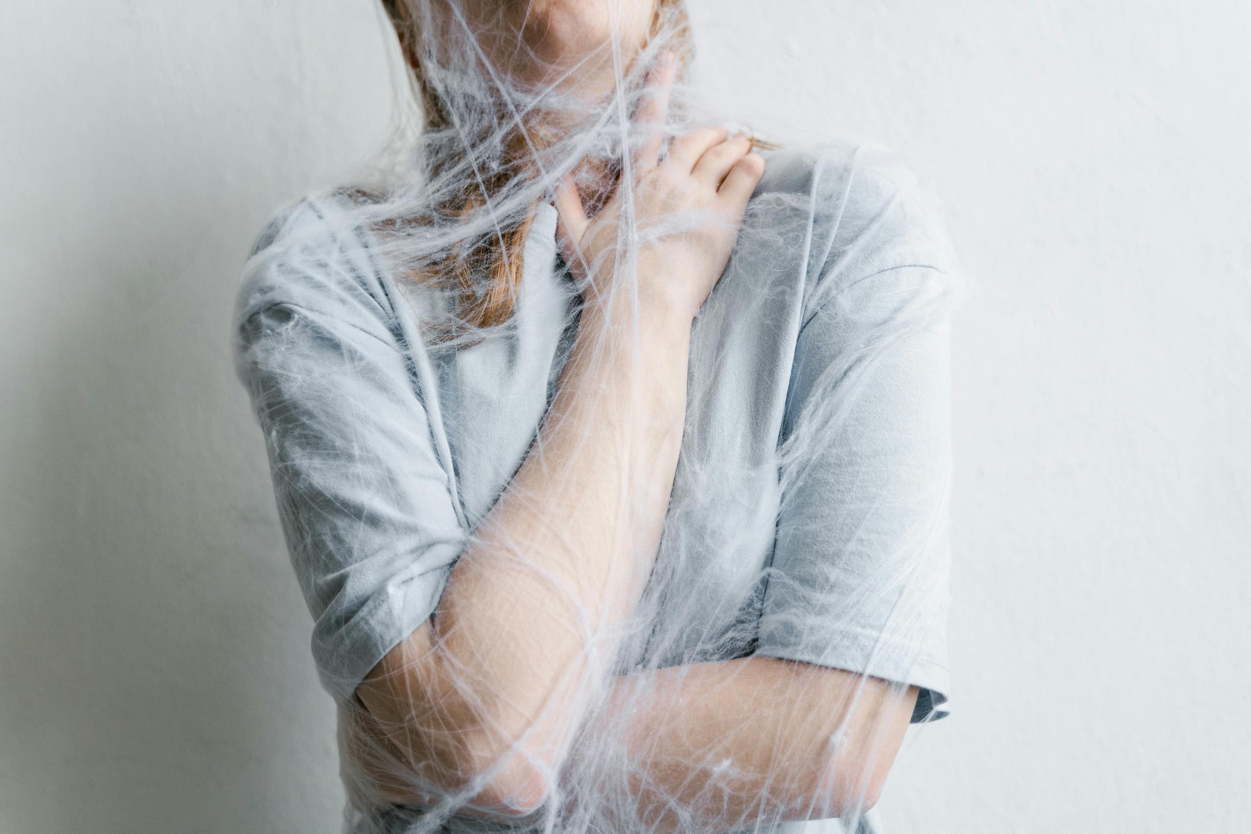 A woman metaphorically trapped in a spider web depicting anxiety and entrapment.