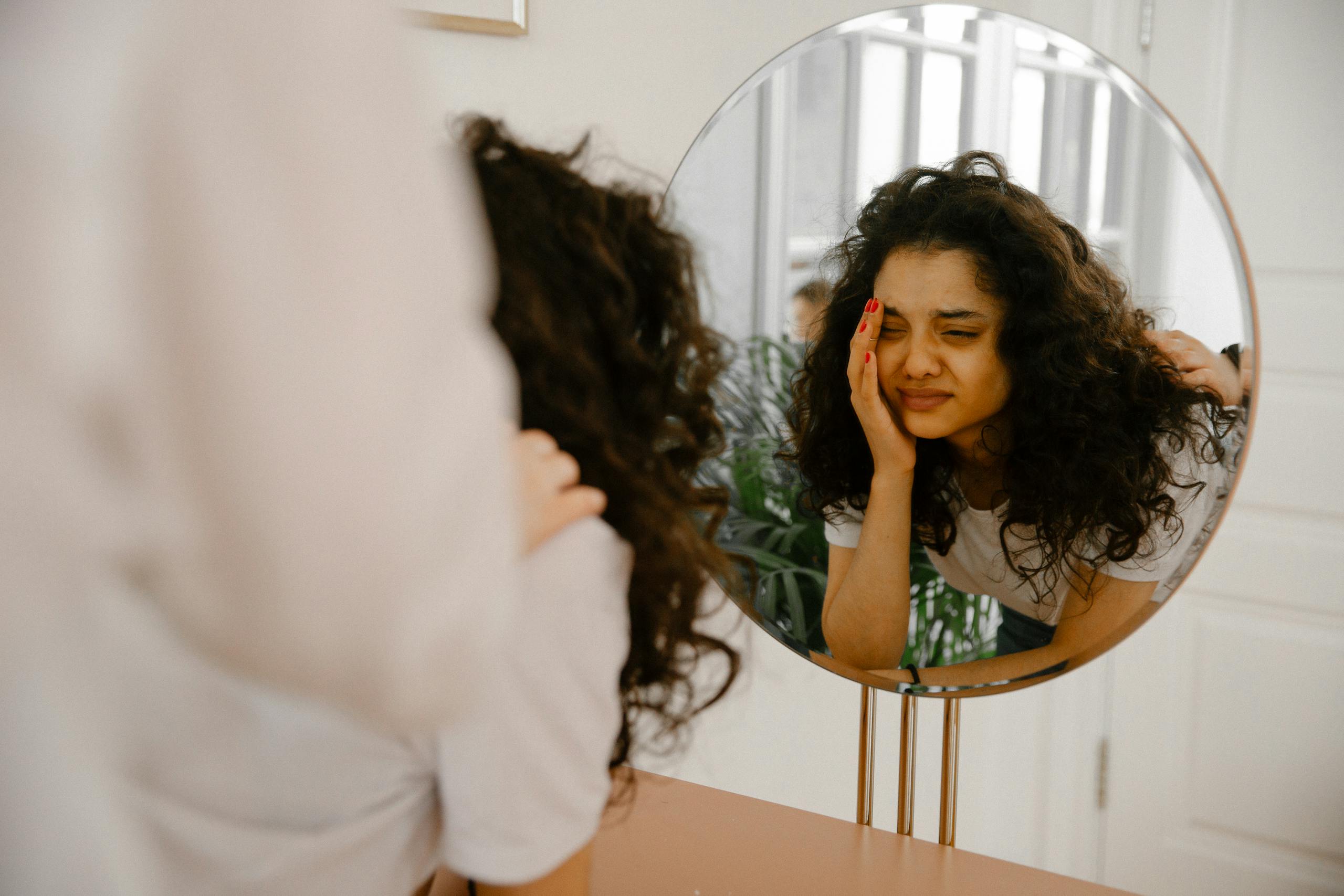 A young woman gazes into a mirror, reflecting her inner emotions and self doubt.
