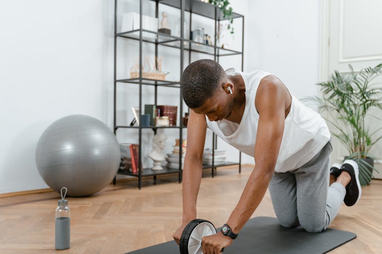 Adult male using an ab wheel for exercise in a home gym setting, focusing on fitness.