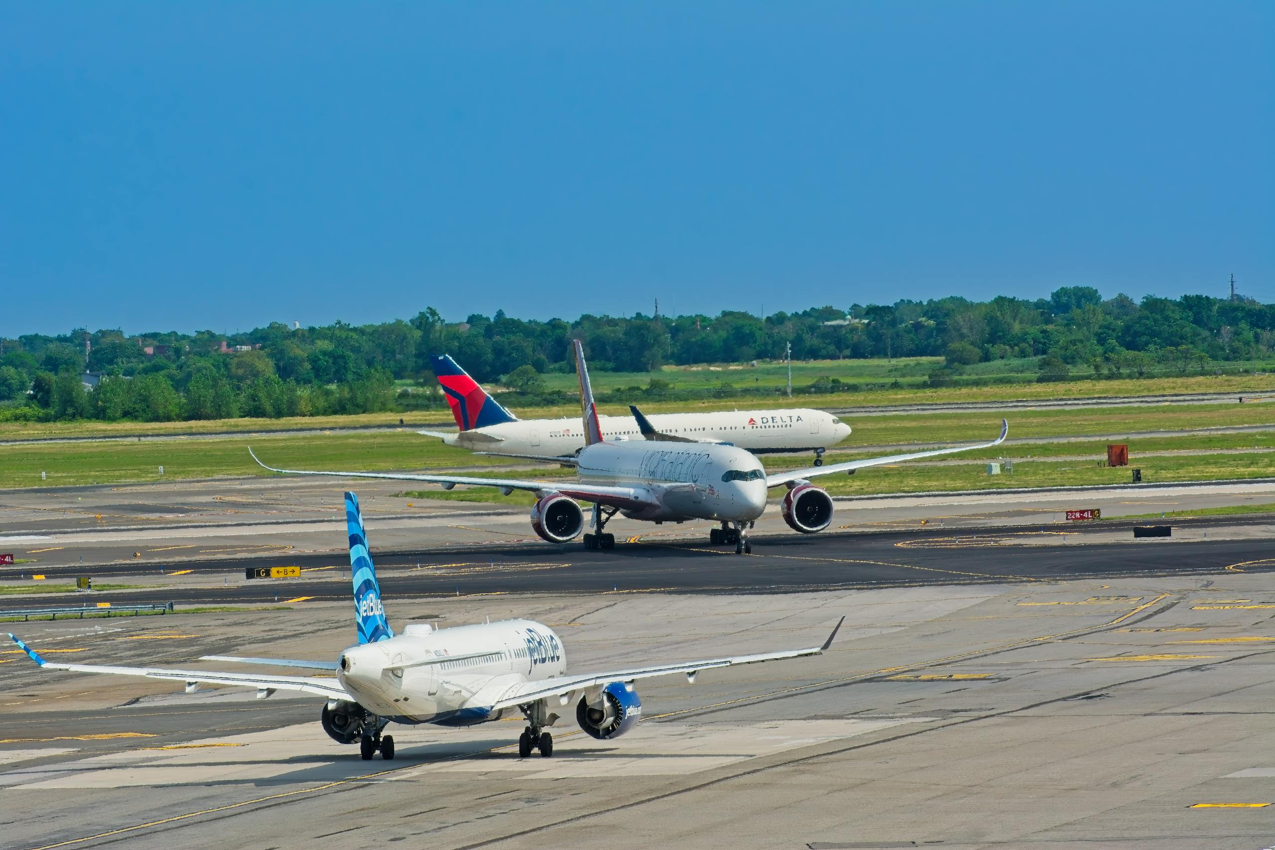 Airplanes from various airlines taxiing on a JFK airport runway in New York.