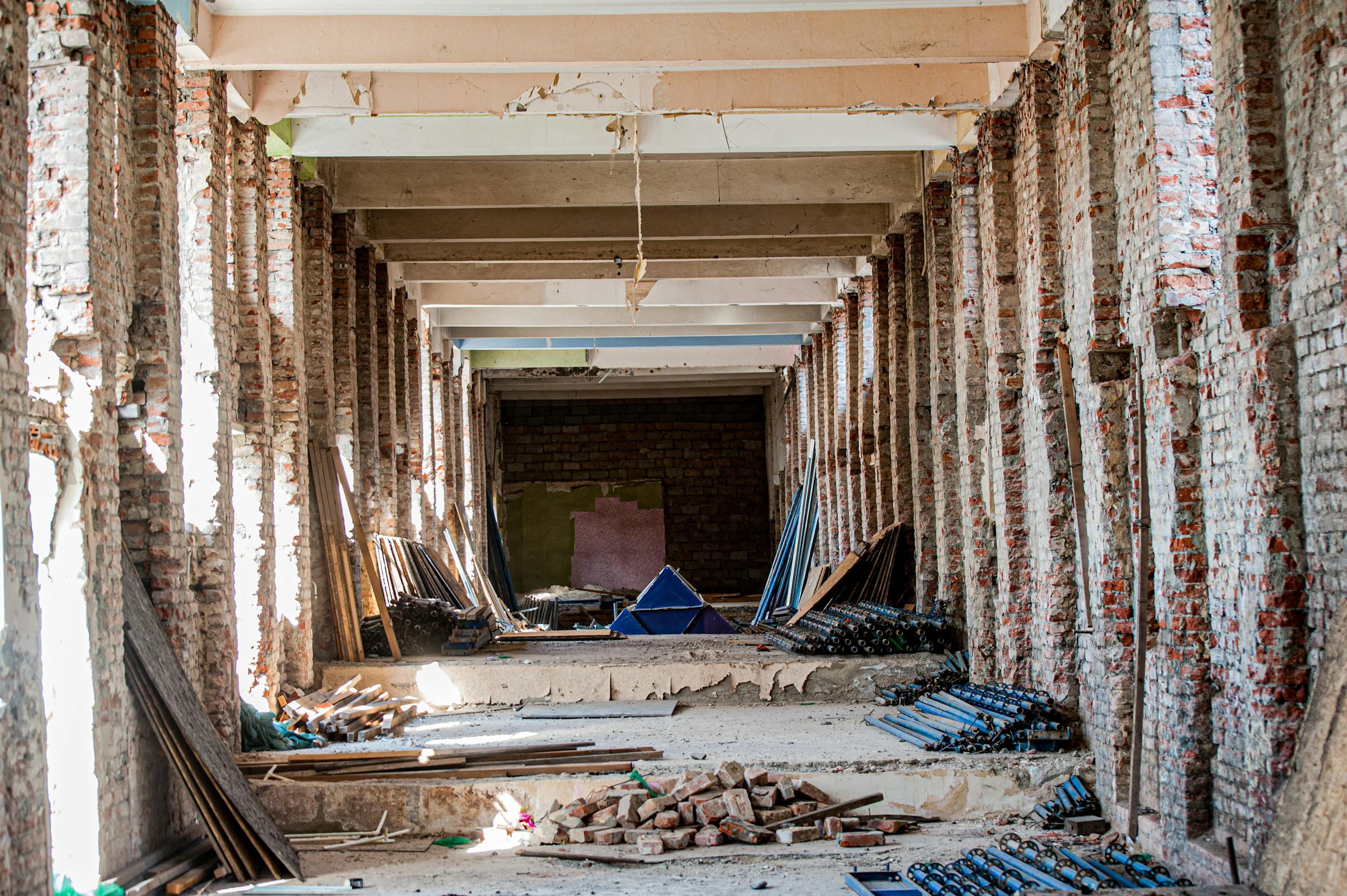 An empty industrial interior undergoing renovation, with exposed brick and construction materials.