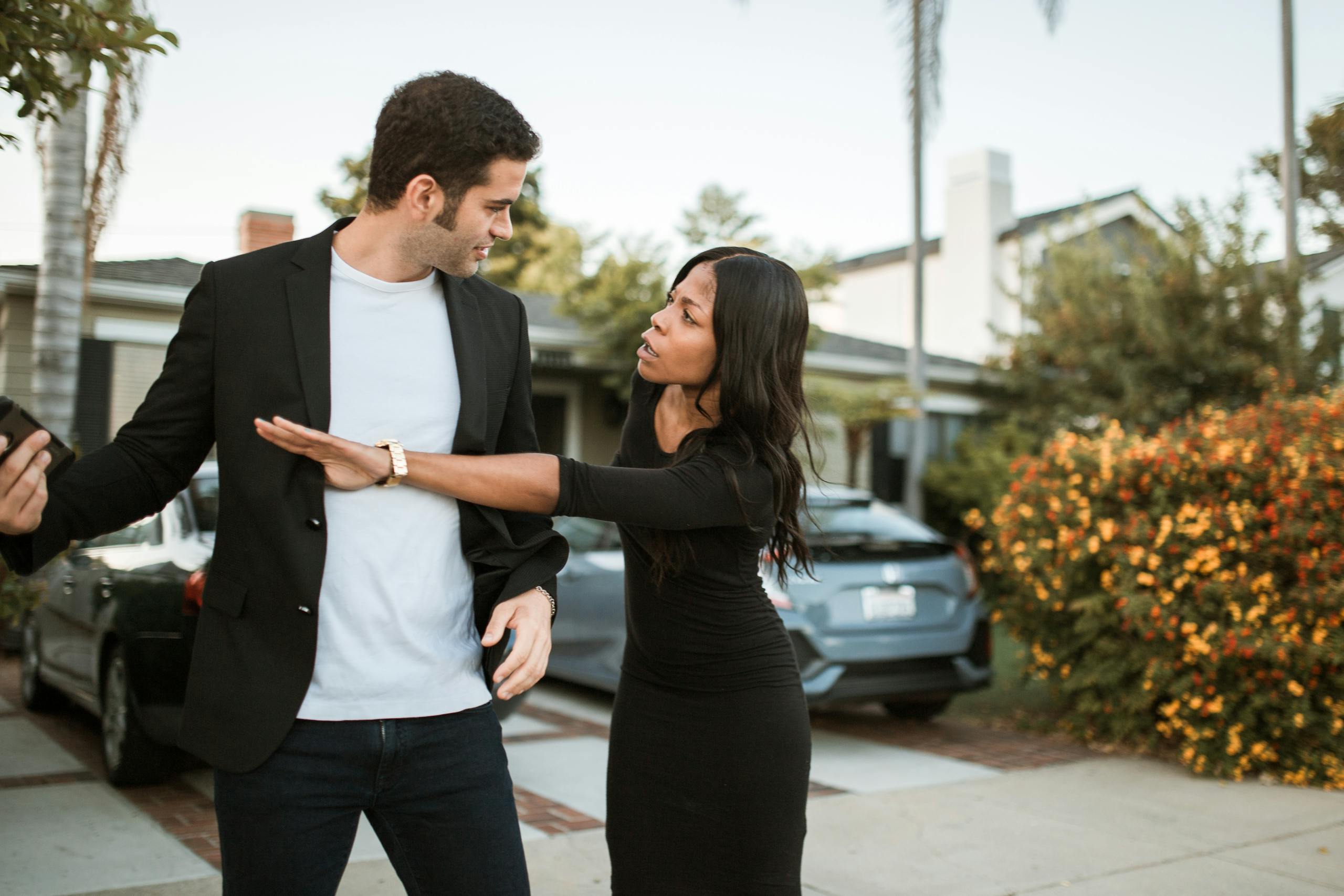 An interracial couple in a heated argument in a suburban neighborhood street.