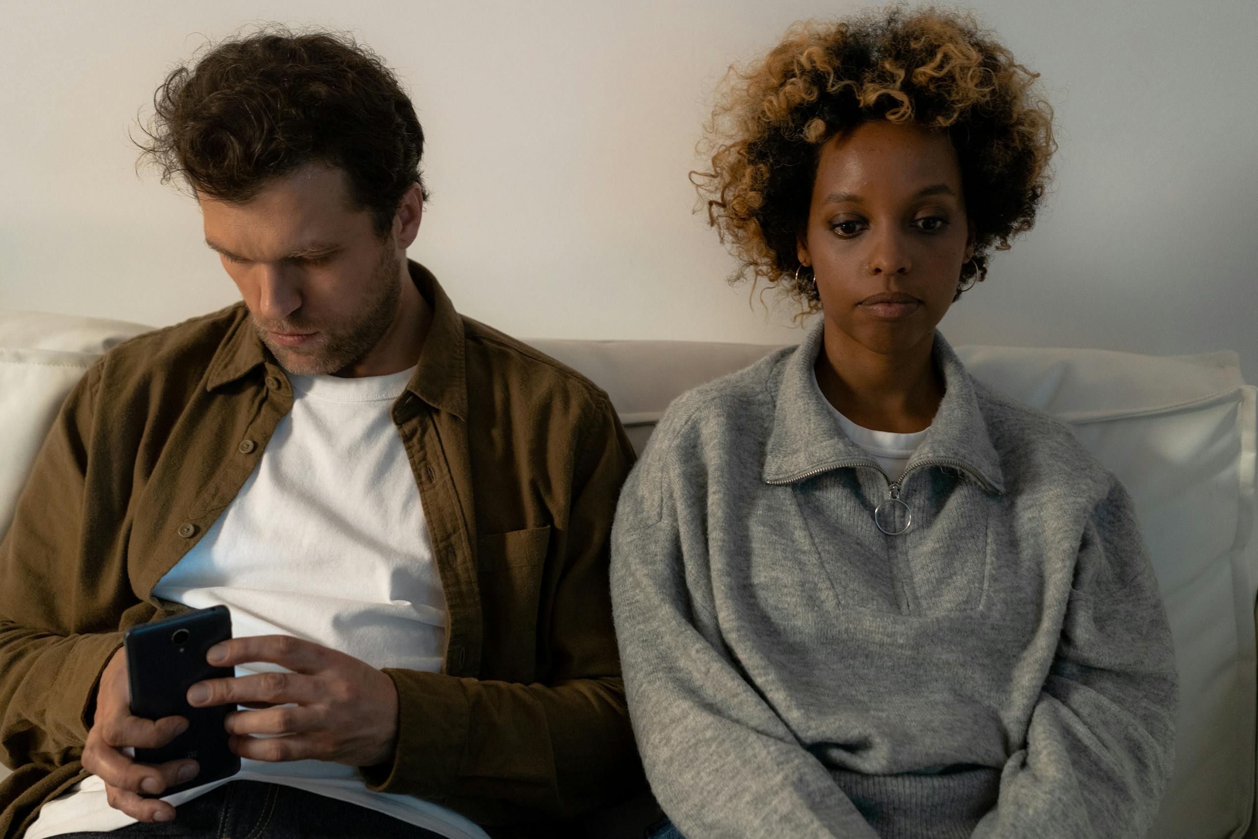 An unhappy couple sitting together on a sofa, each lost in their thoughts.
