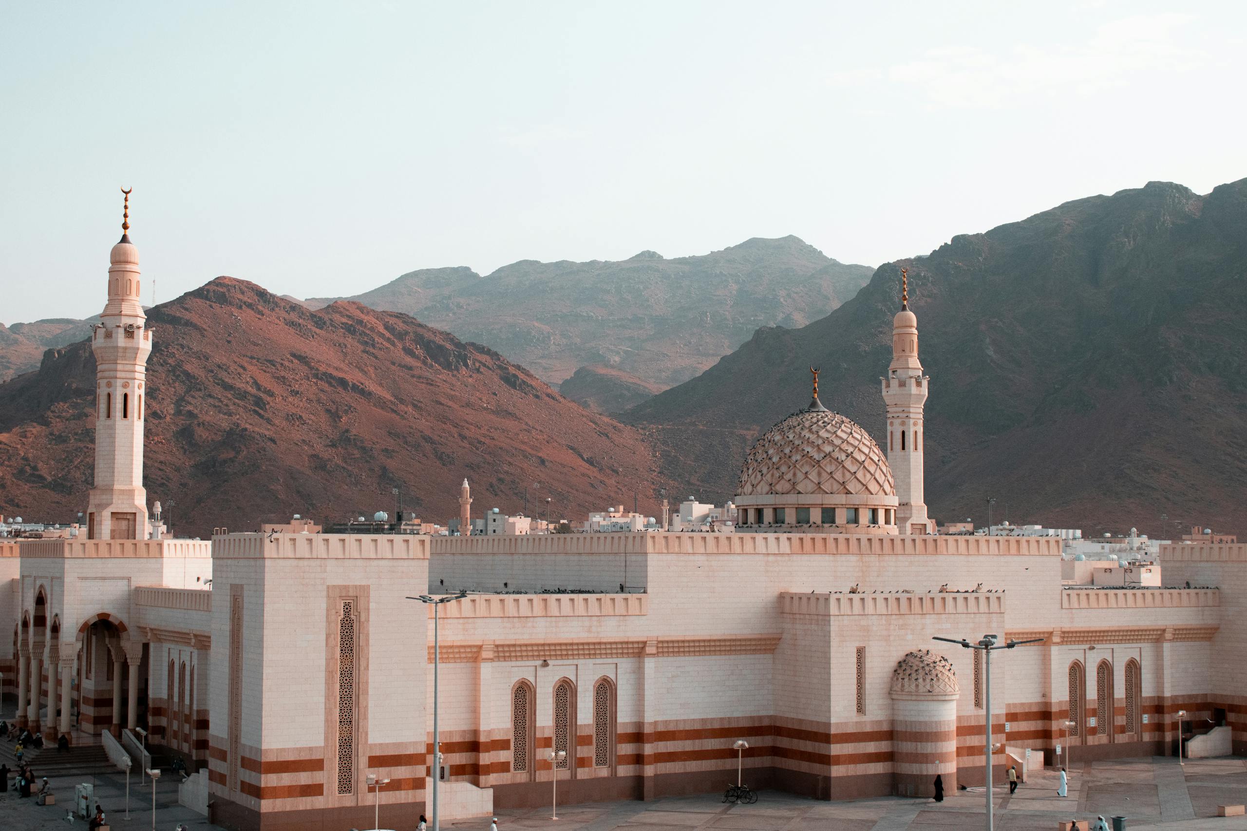 Beautiful mosque with minarets stands against rugged mountain landscape, Saudi Arabia.