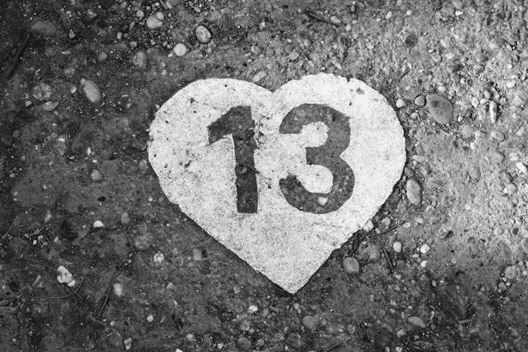 Black and white photo of a heart-shaped number 13 on a pebbled ground in Budapest.