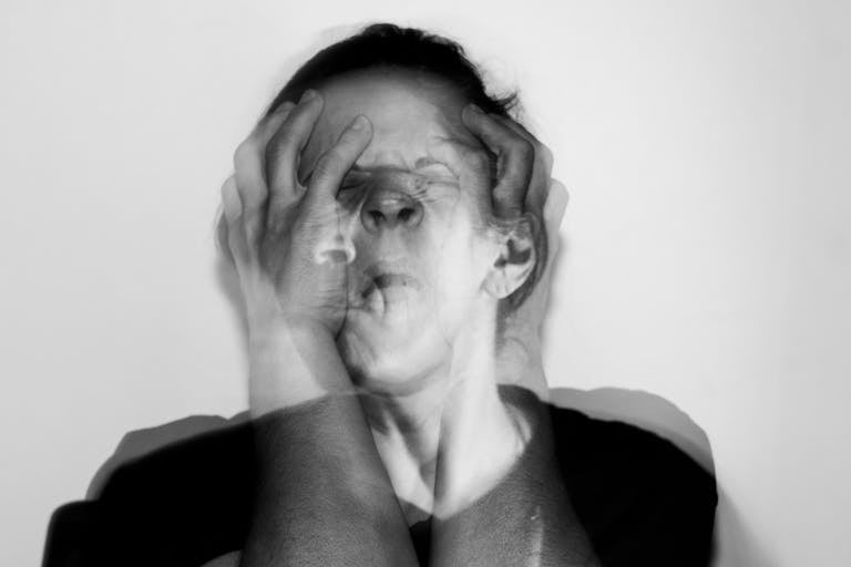 Black and white portrait capturing intense emotion through double exposure technique.