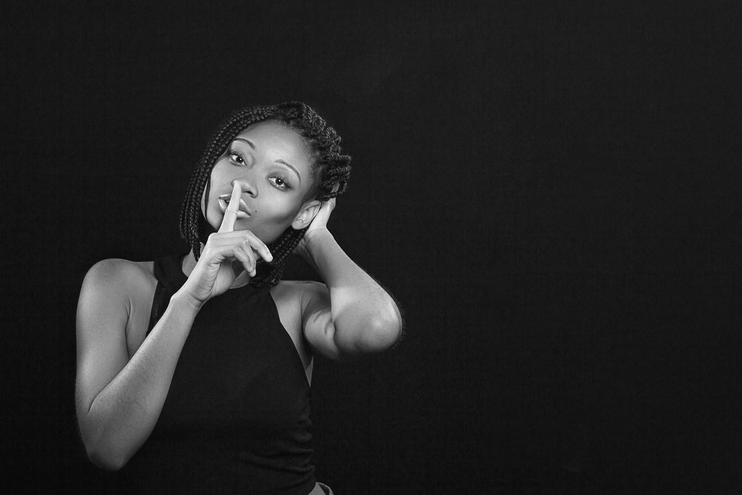 Black and white portrait of a woman with braided hair posing in studio.
