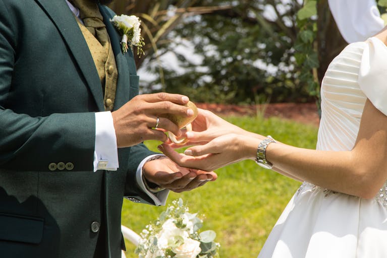 Bride and groom exchanging rings in an elegant outdoor wedding ceremony.