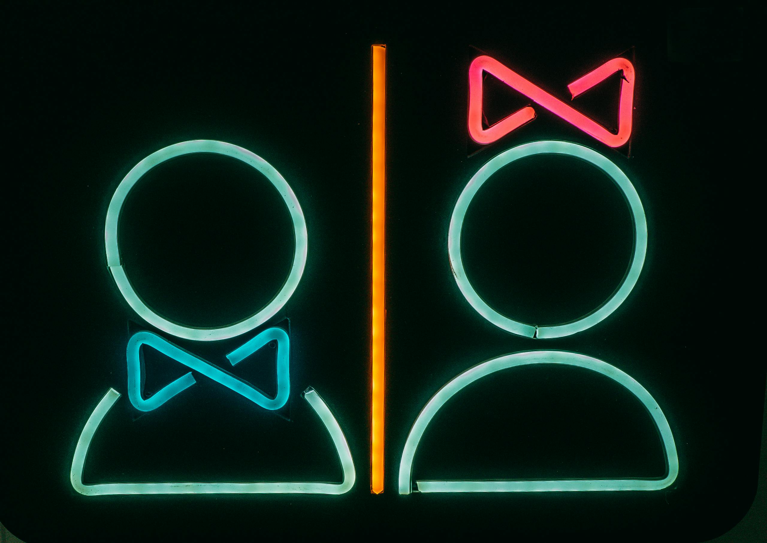Bright neon bathroom sign with male and female symbols, vibrant and modern.