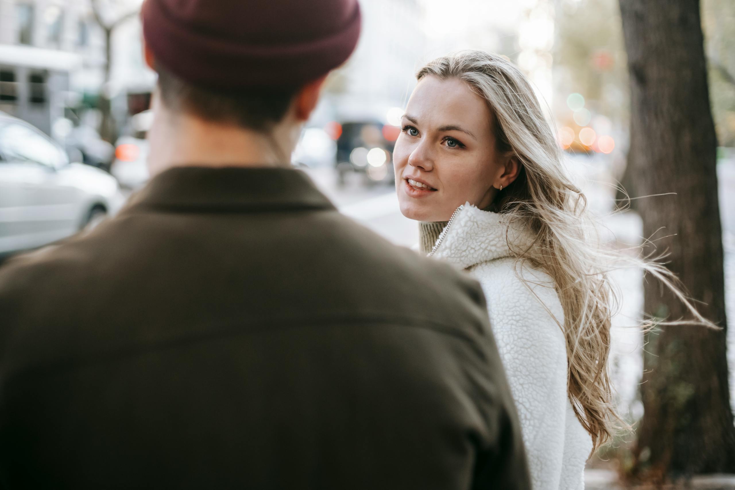 Calm couple in warm casual wear talking on city street in autumn day