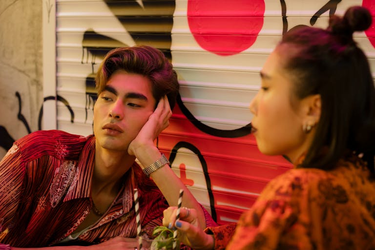 Chic couple enjoying drinks in a vibrant, modern cafe with artistic graffiti backdrop.