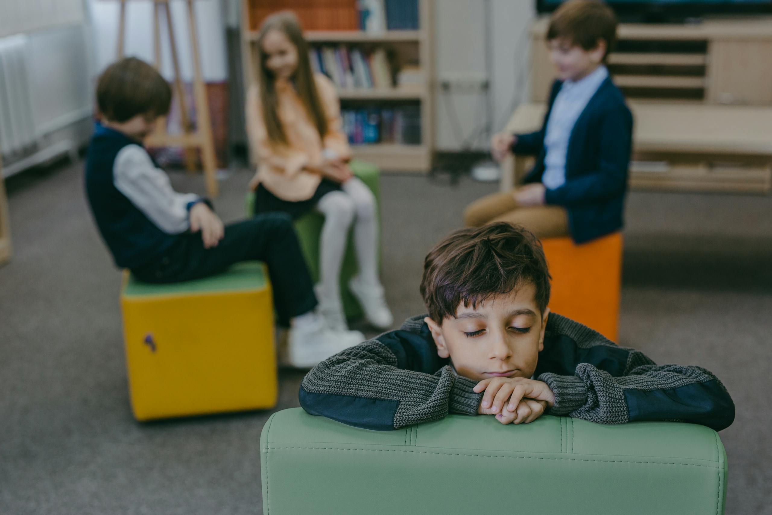 Child feeling isolated in a classroom while peers interact. Emphasizes themes of loneliness and social dynamics.
