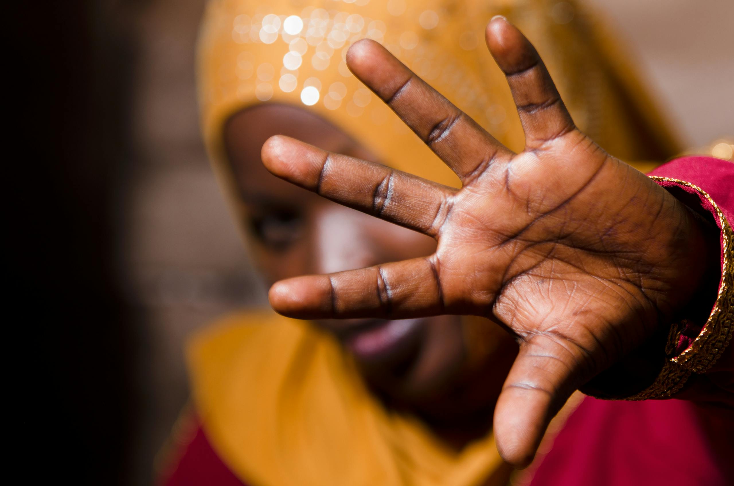 Close-up hand gesture of a woman in colorful attire, highlighting cultural expression.