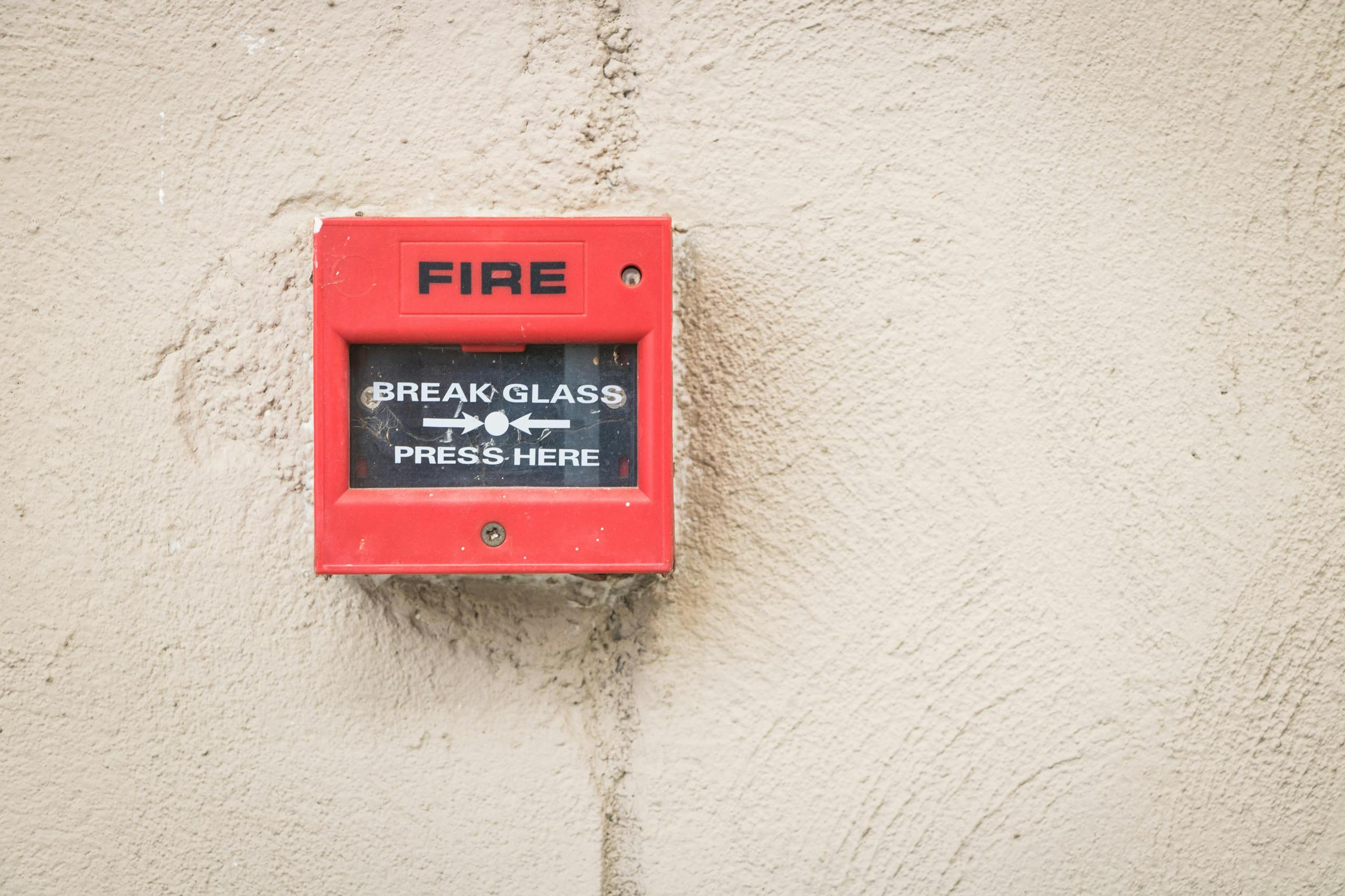 Close-up of a red fire alarm mounted on a textured wall, ready for emergency use.