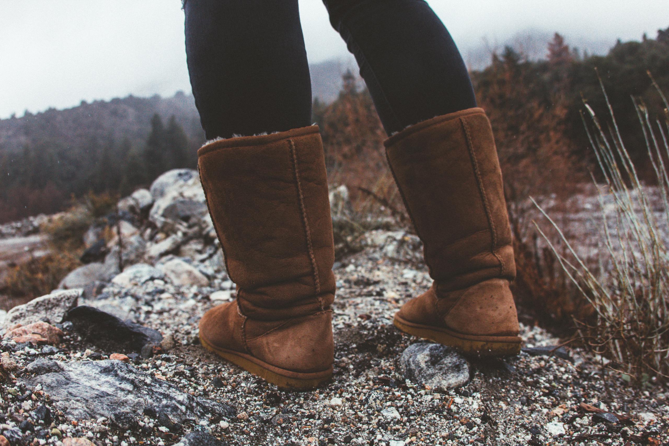 Close-up of brown boots on rocky outdoor path during fall hike.