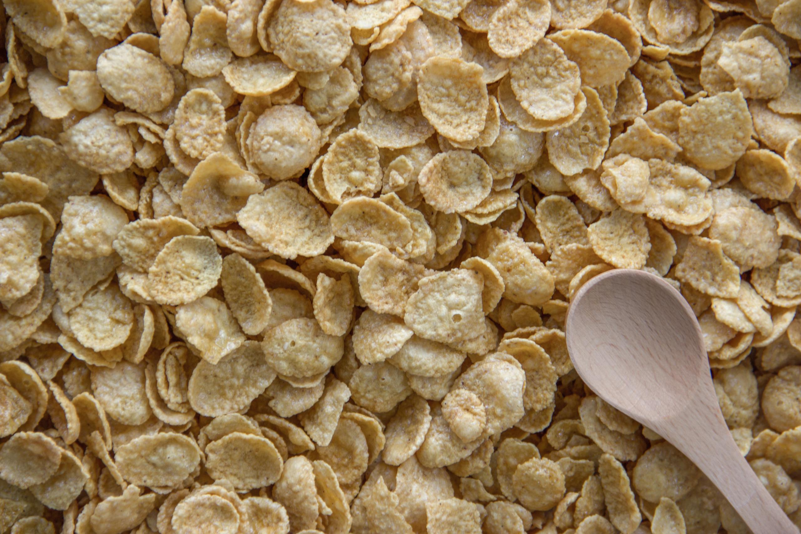 Close-up of cornflakes with a wooden spoon, highlighting a healthy breakfast option.