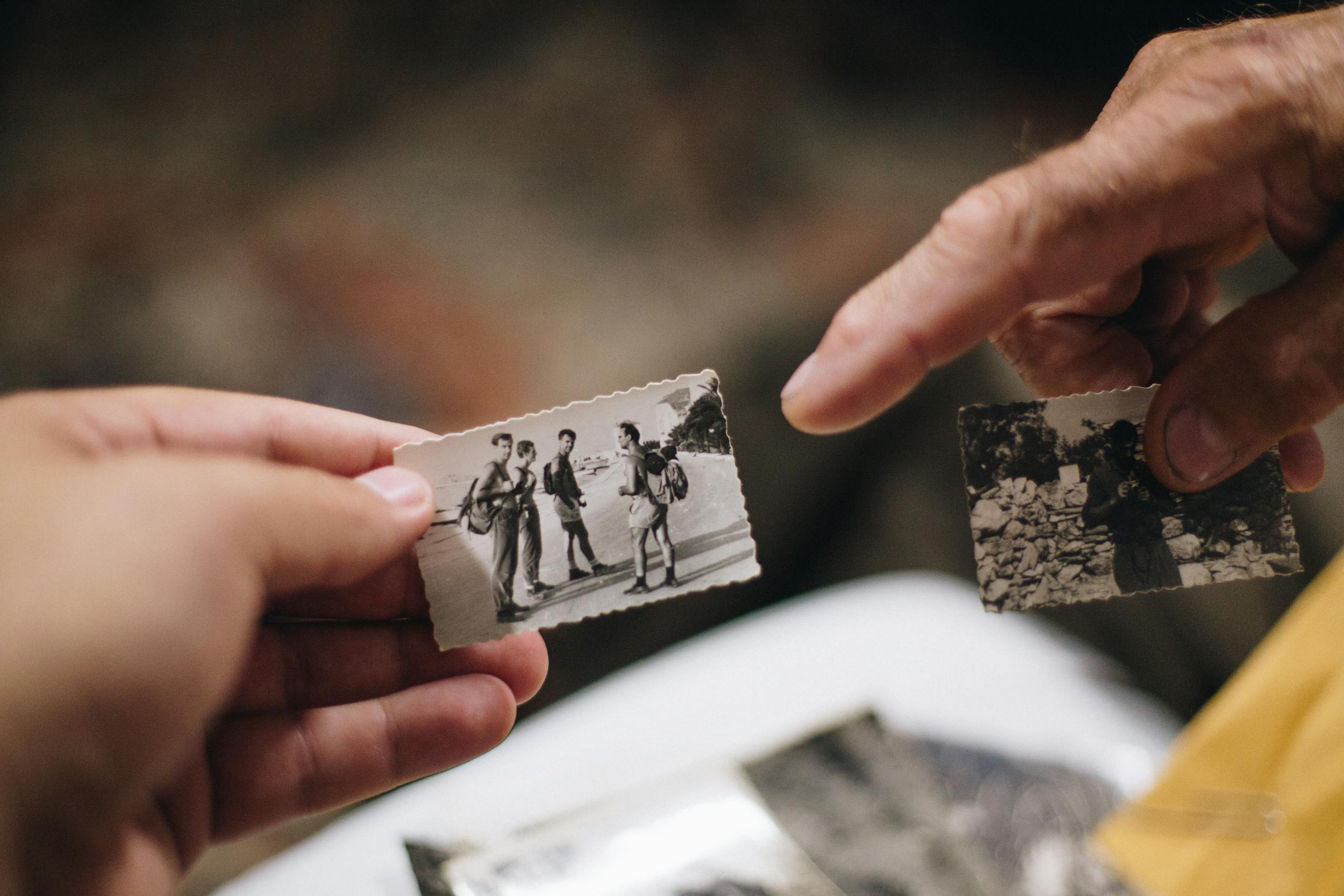 Close-up of hands holding vintage black and white photos, evoking nostalgia and memories.