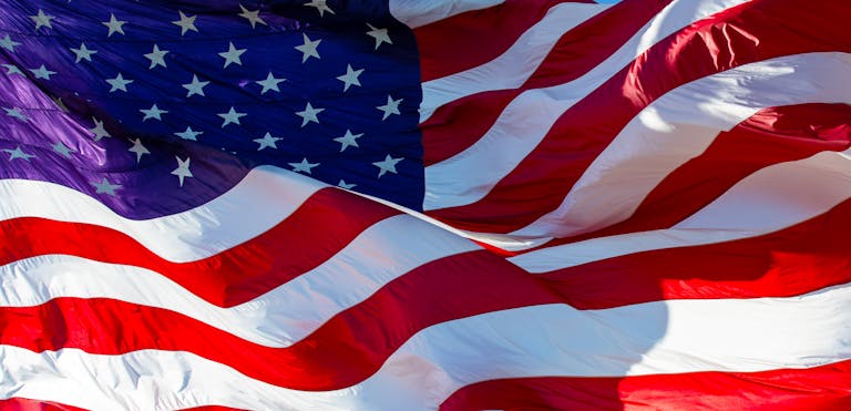 Close-up of the American flag waving majestically in bright sunlight, symbolizing patriotism.