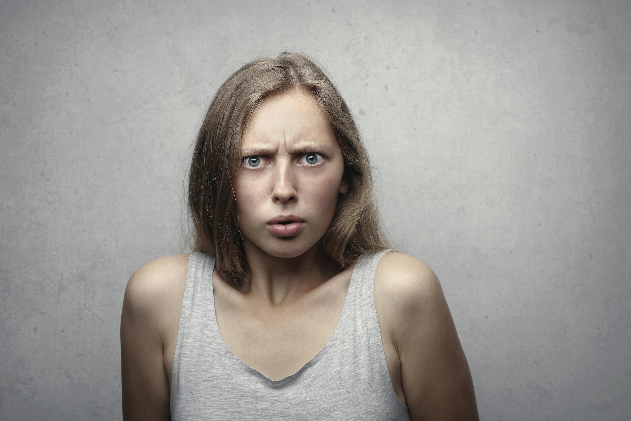 Close-up portrait of a pensive woman with a confused facial expression indoors.