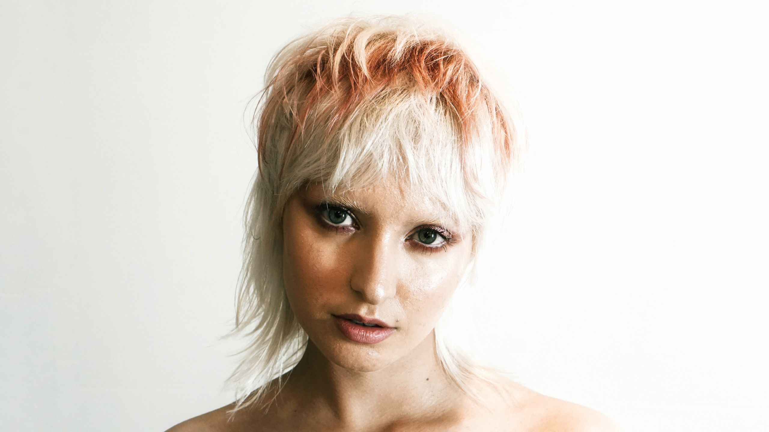 Close-up portrait of a woman with a modern haircut against a light background.