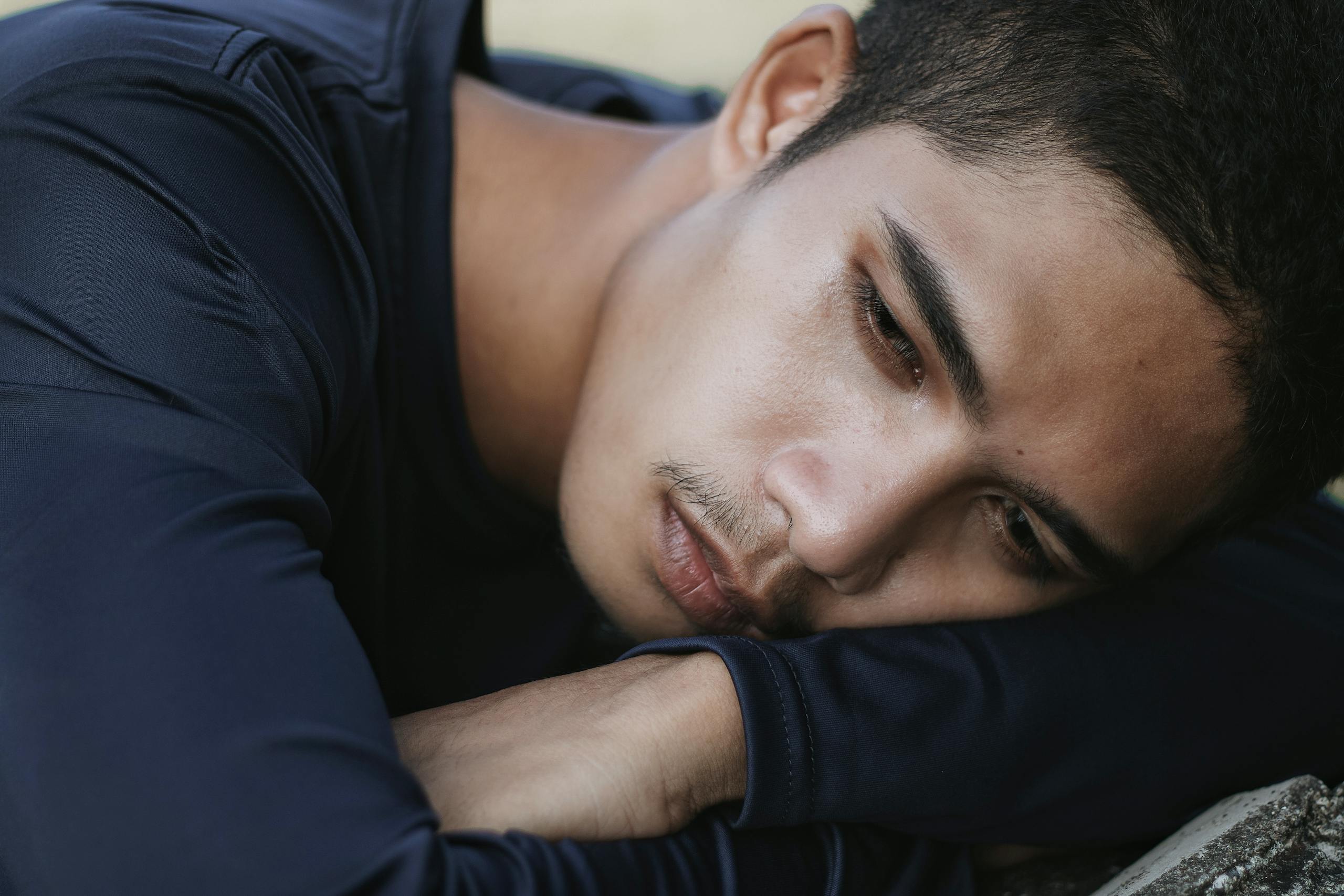 Close-up portrait of a young man expressing deep emotional introspection.