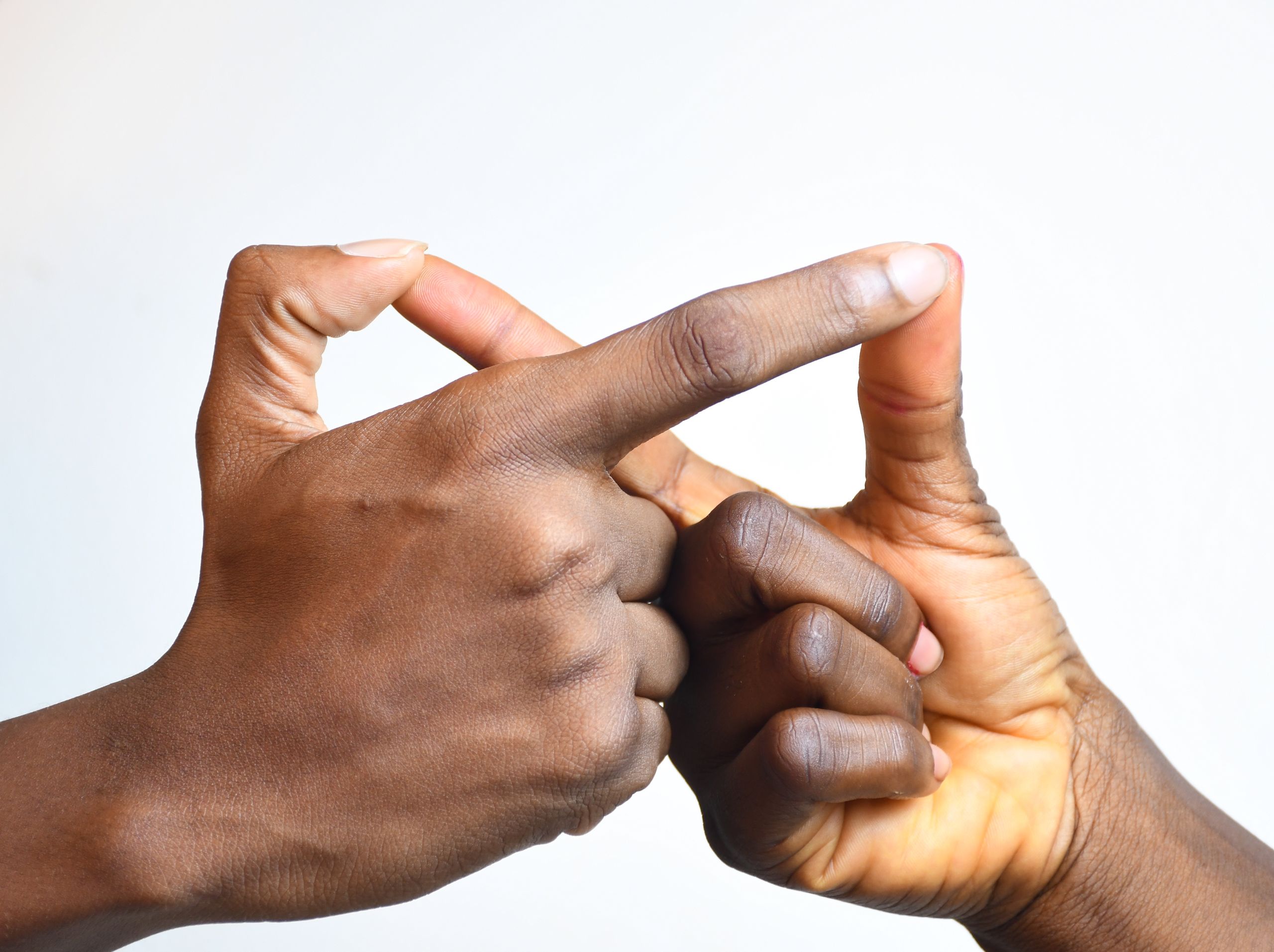 Close-up view of two black hands crossing fingers in a gesture. High detail skin texture.