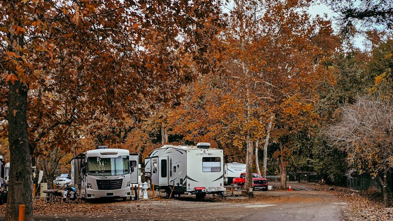 Cozy RV campsite surrounded by vibrant fall foliage in a serene forest.