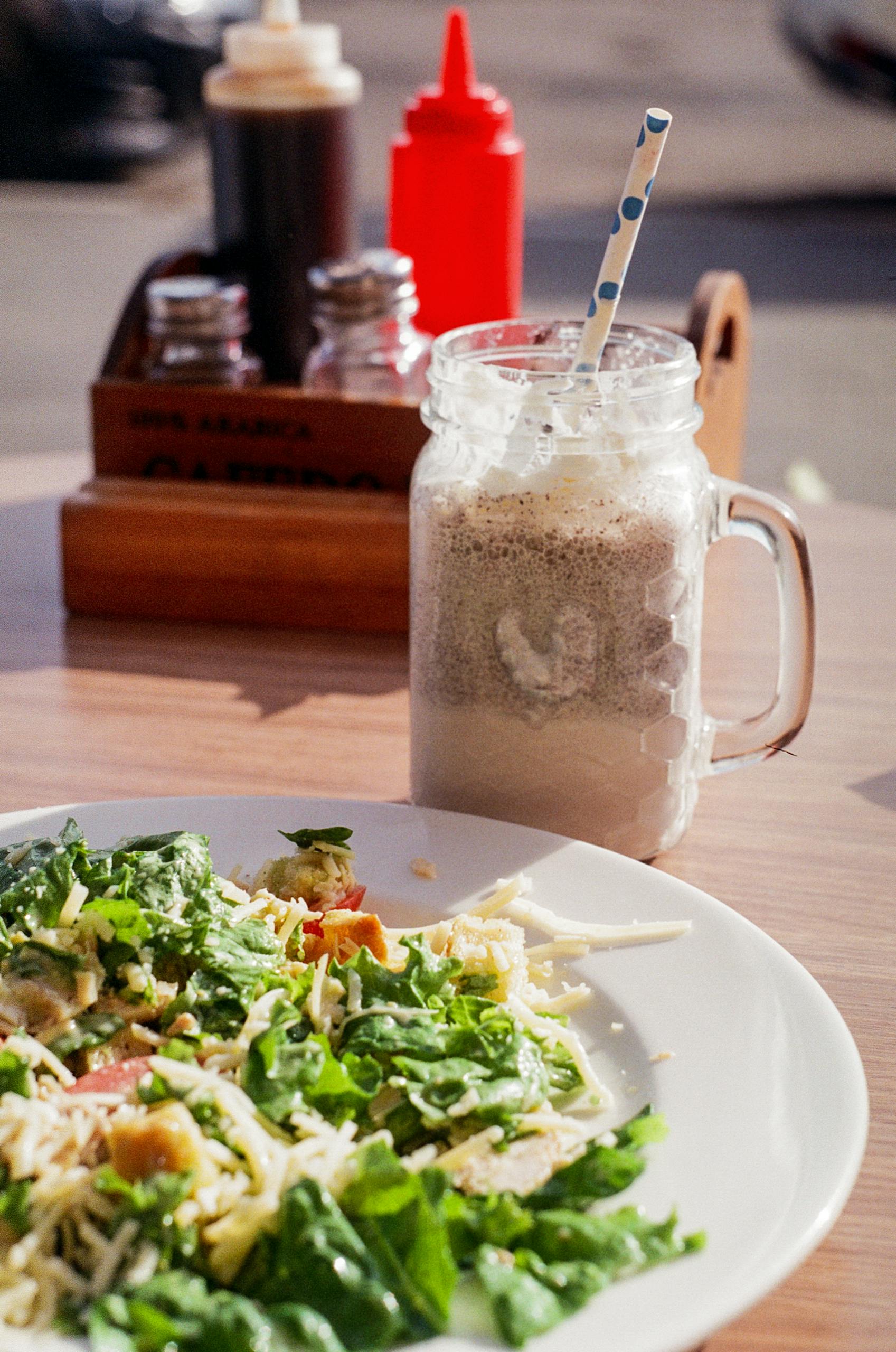 Delicious Caesar salad paired with a frothy chocolate milkshake on a sunny day.