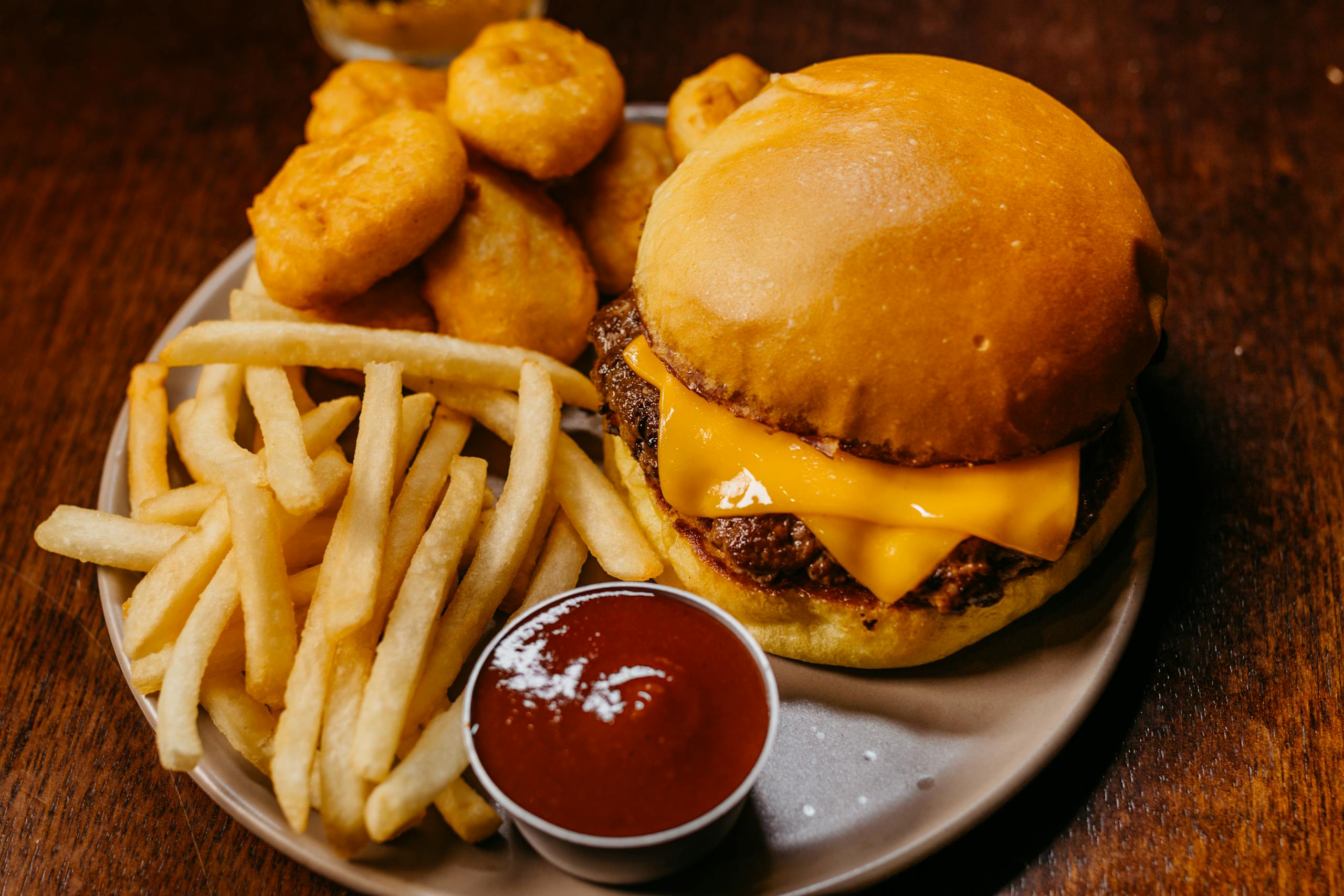 Delicious cheeseburger with fries, nuggets, and ketchup on a plate.