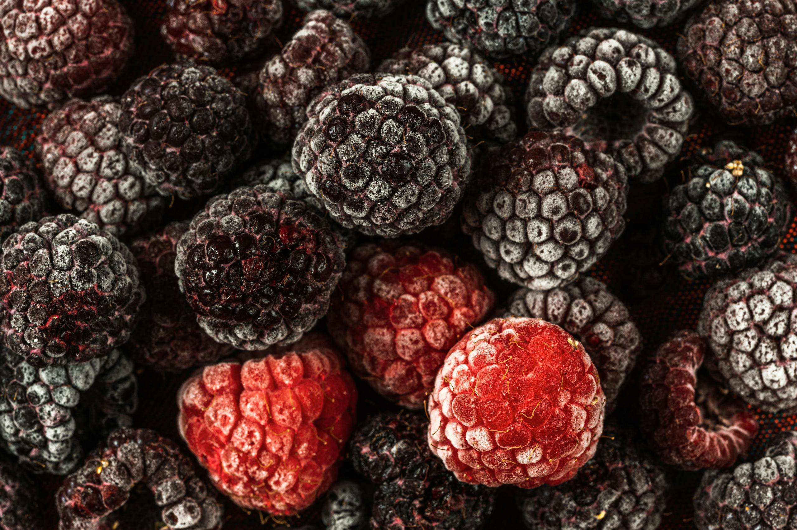 Detailed close-up of frozen raspberries and blackberries showcasing their texture and icy appearance.