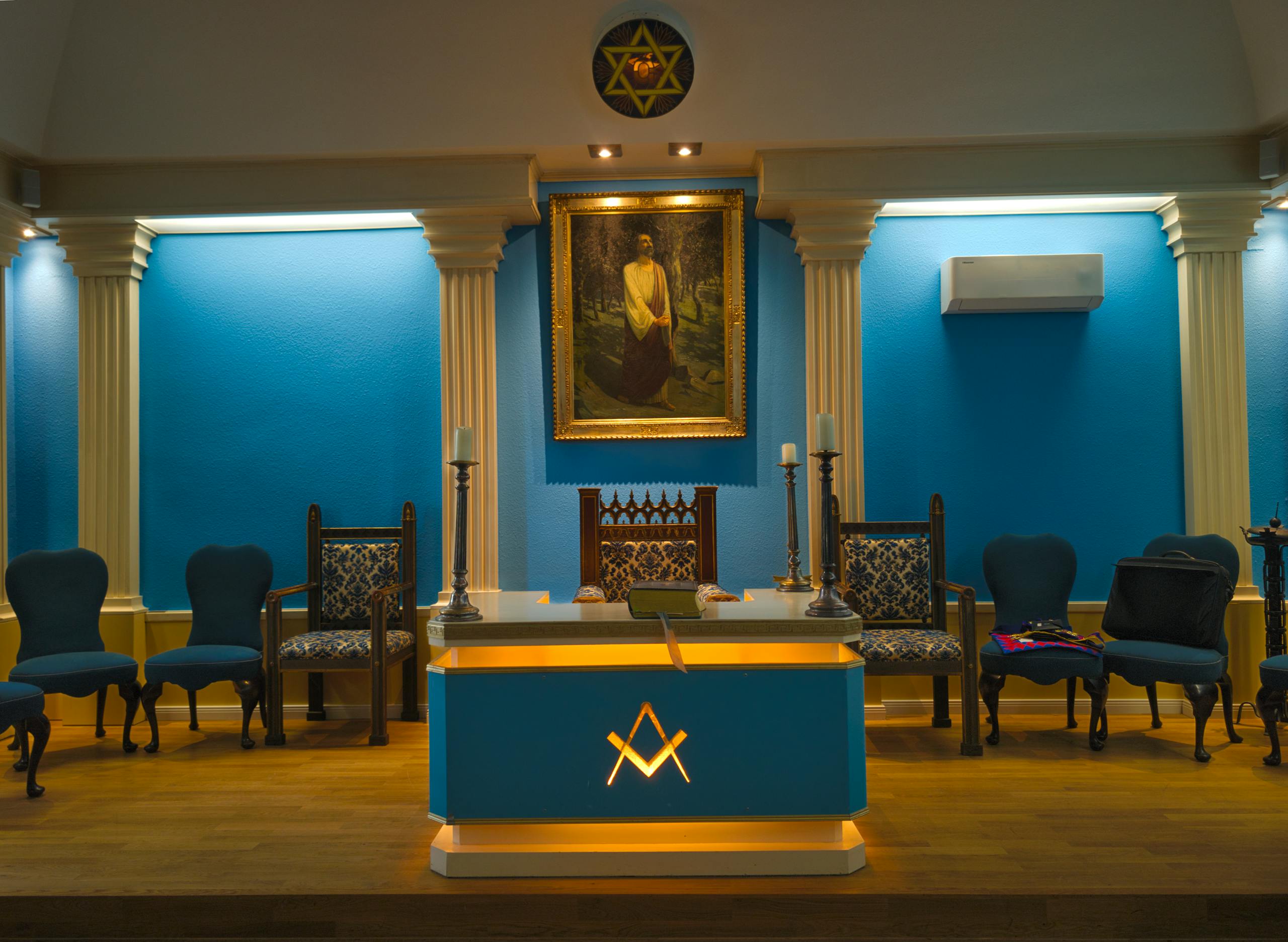 Detailed view of a Masonic lodge with blue decor, seating, and symbolic items.