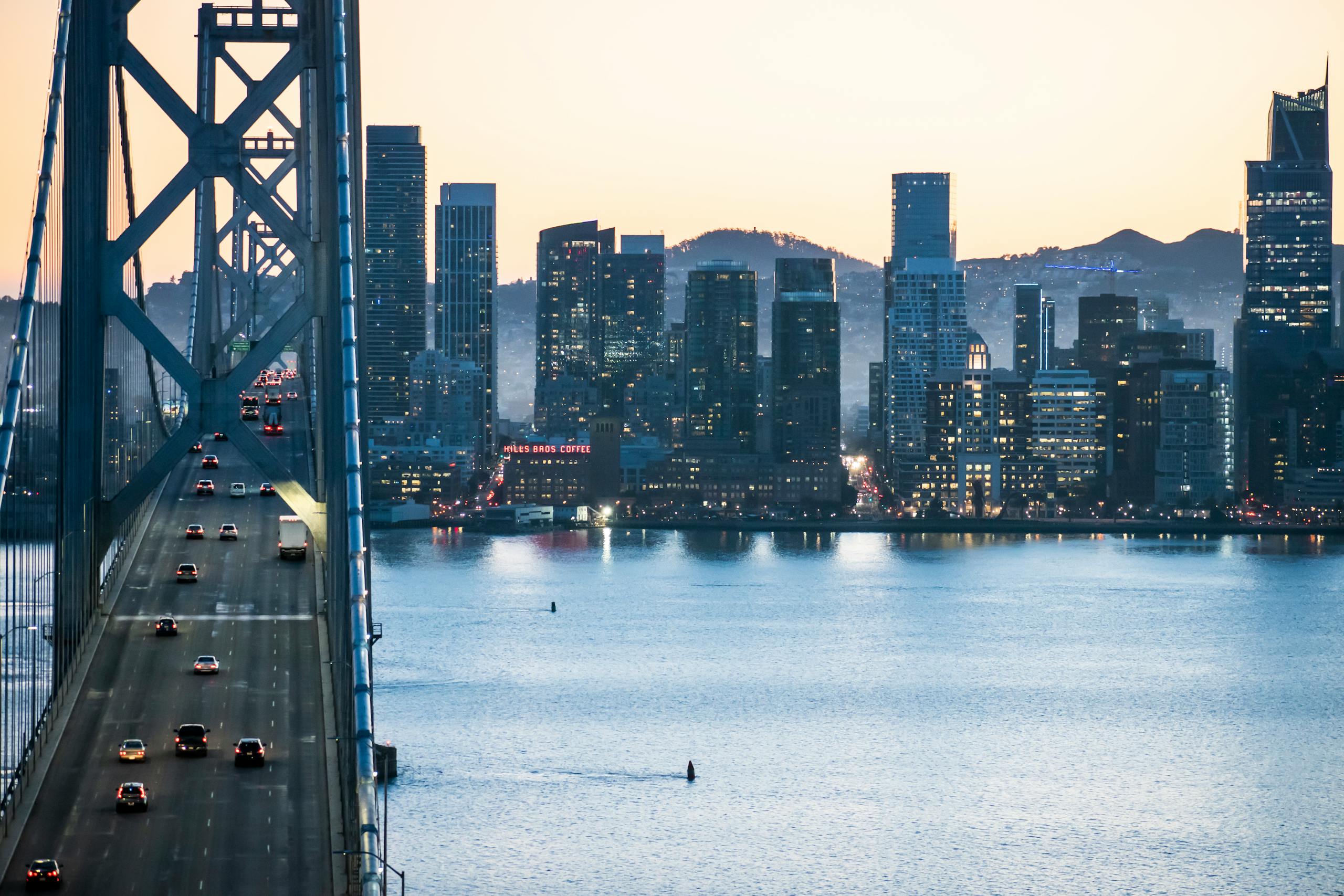Dusk view of San Francisco skyline with the Bay Bridge and waterfront, showcasing urban architecture.