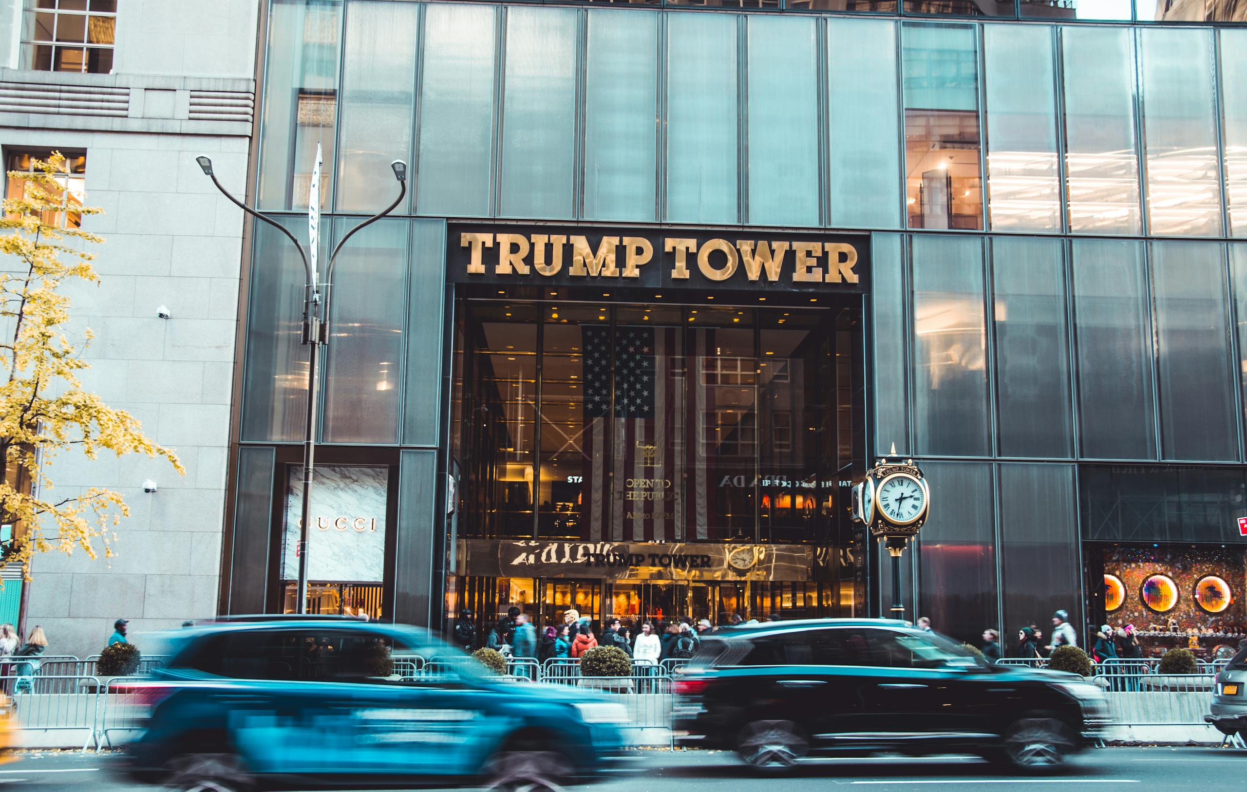 Dynamic view of Trump Tower's entrance with bustling street traffic in New York City.
