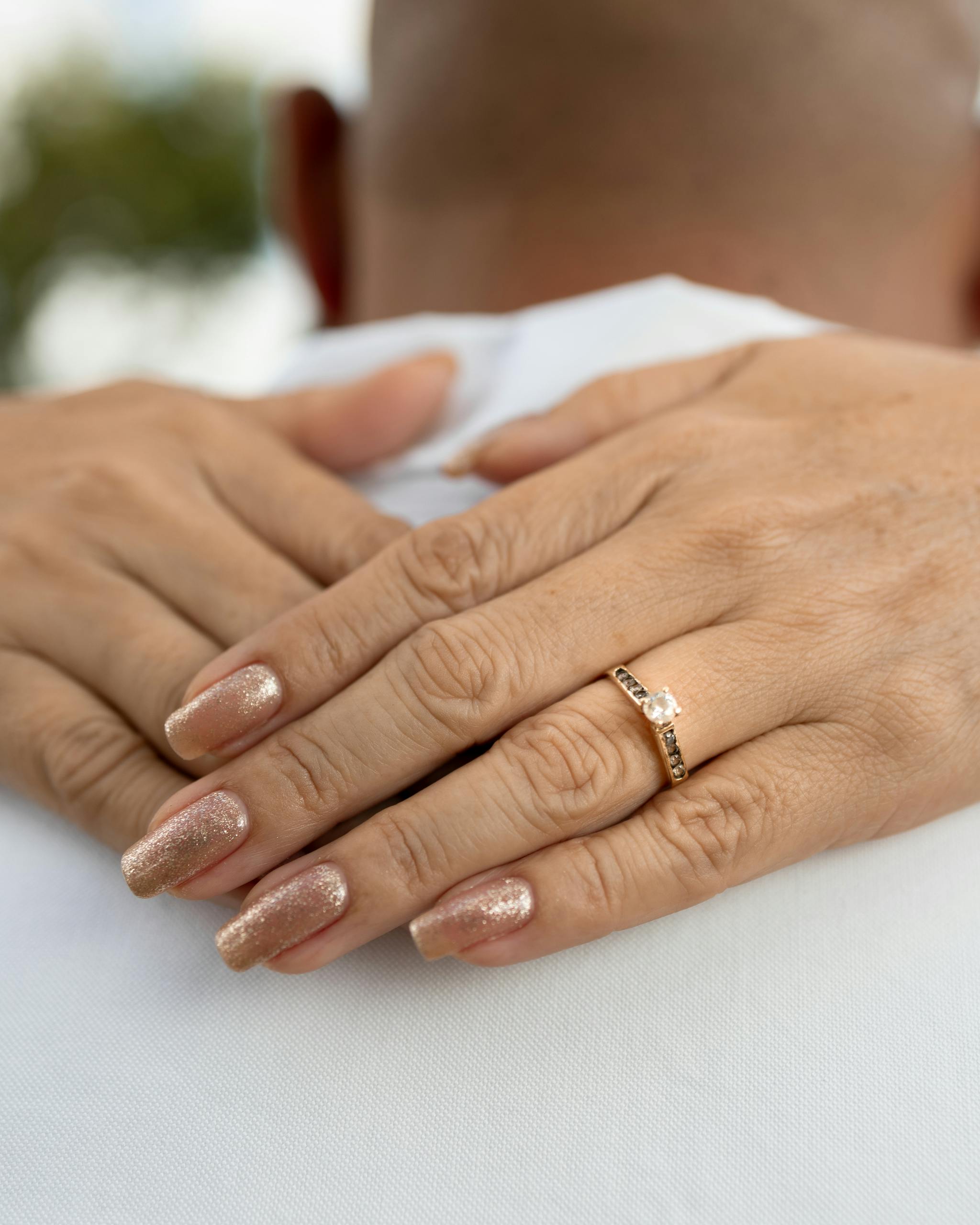 Elegant close-up of a woman's hands showing an engagement ring outdoors, perfect for wedding themes.