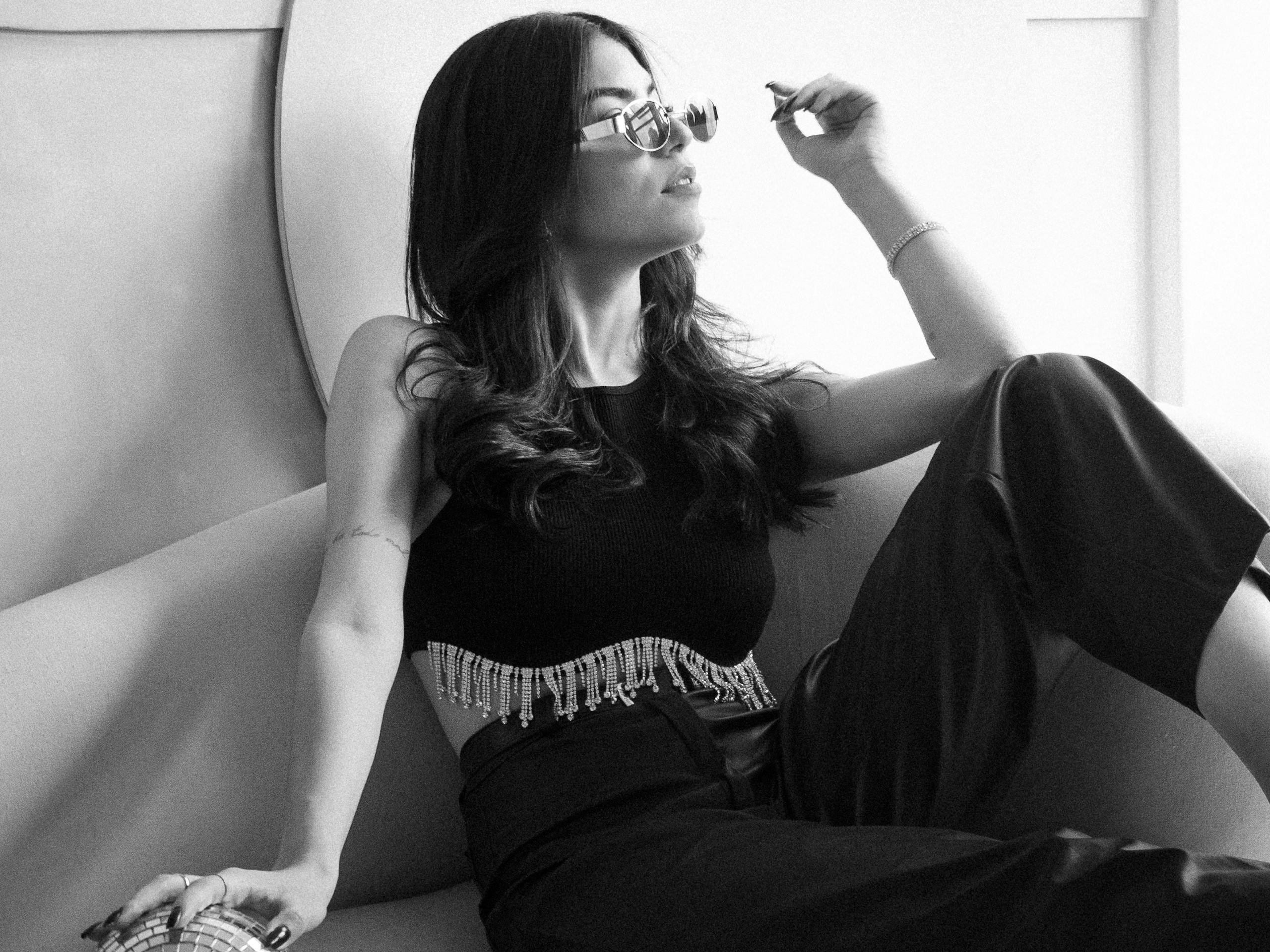 Elegant woman lounging on sofa in chic outfit, captured in monochrome for a classic look.