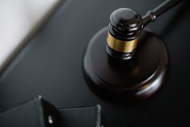 From above of wooden gavel on round surface near folders on table in courtroom