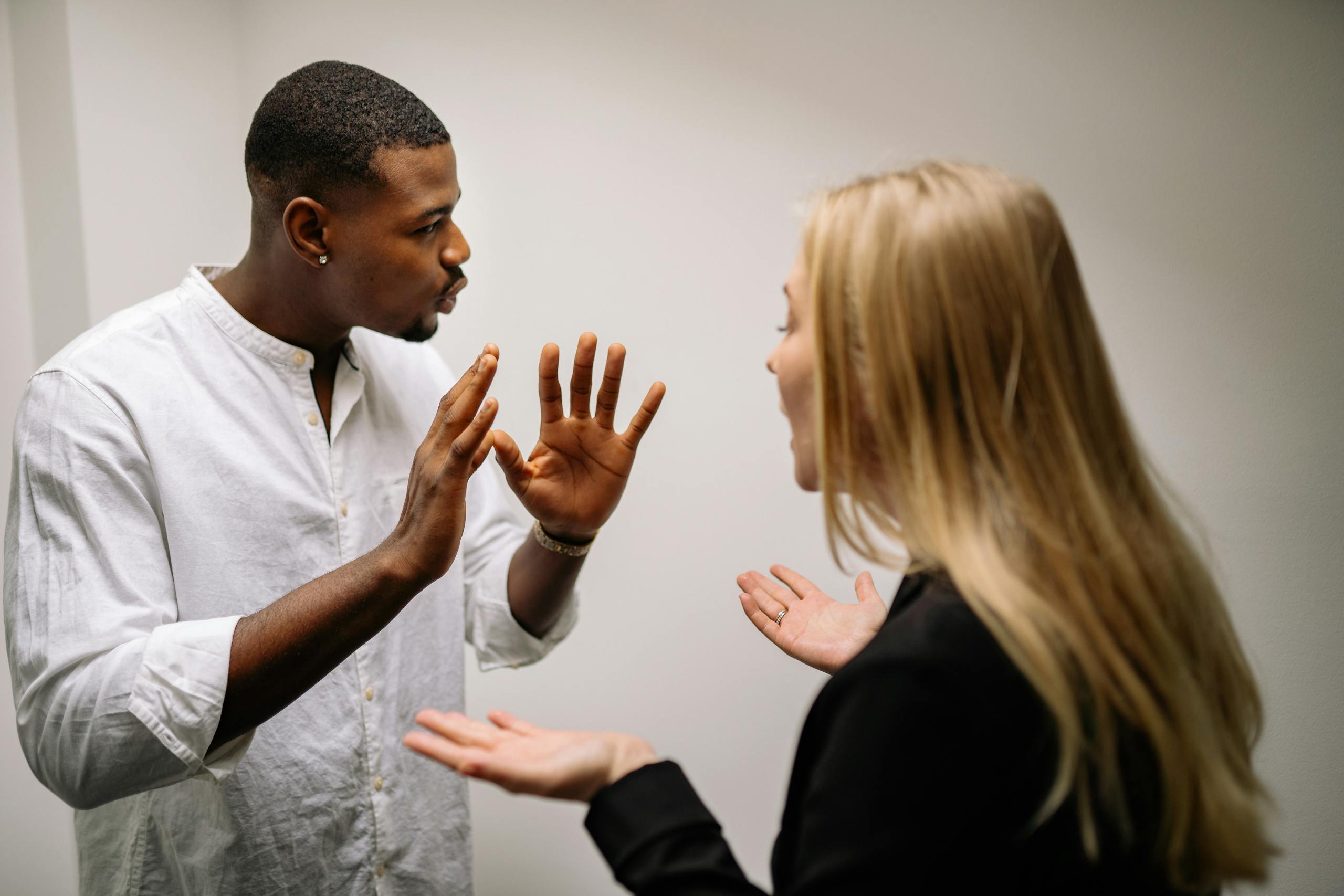 Frustrated coworkers in heated discussion, expressing disagreement in office setting.