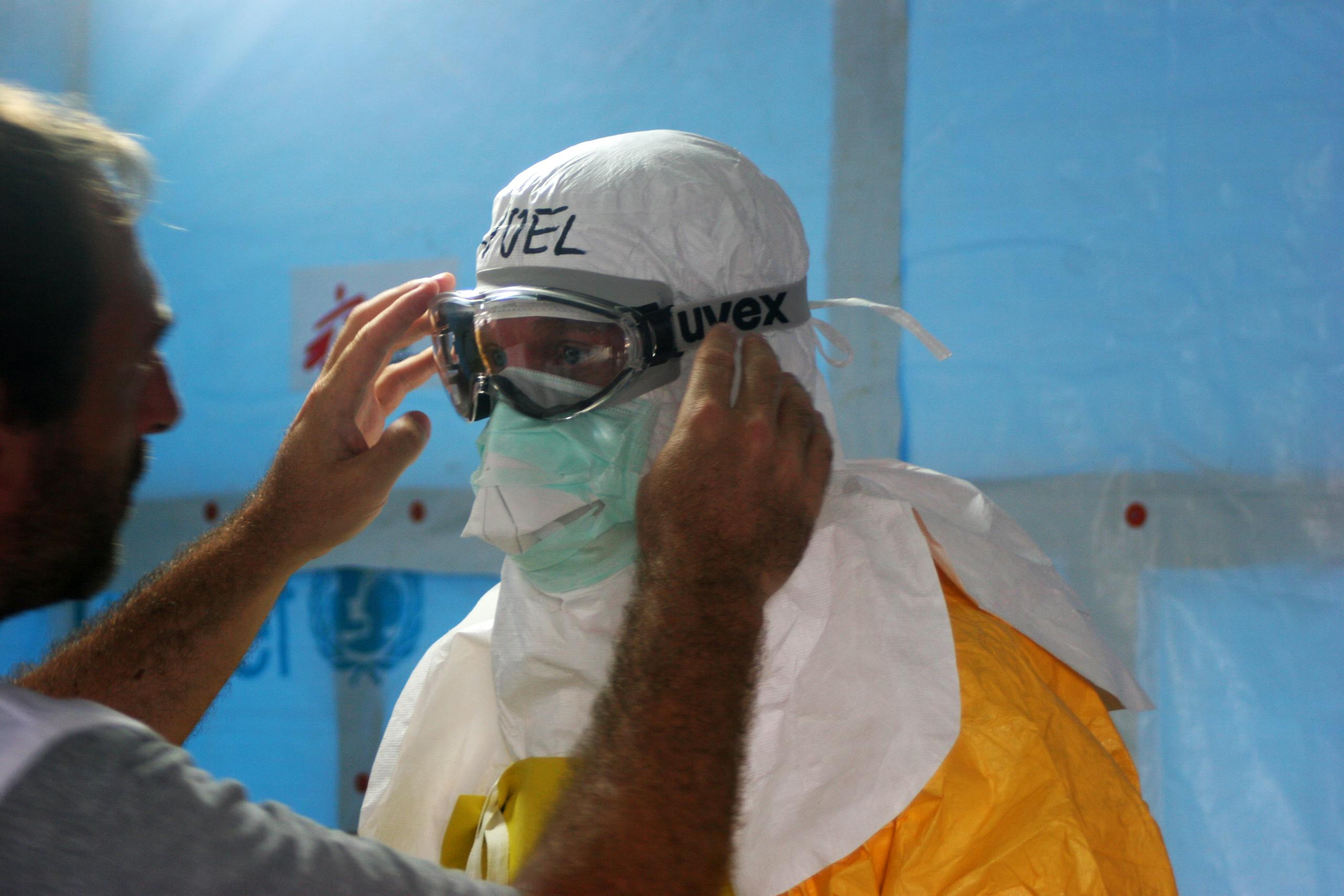 Healthcare worker puts on PPE gear in a medical facility for safety and protection.
