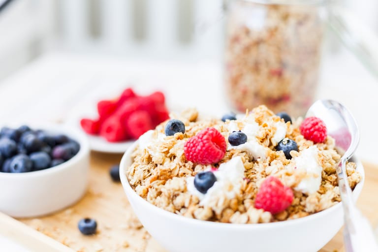 Healthy granola breakfast bowl topped with fresh raspberries and blueberries.