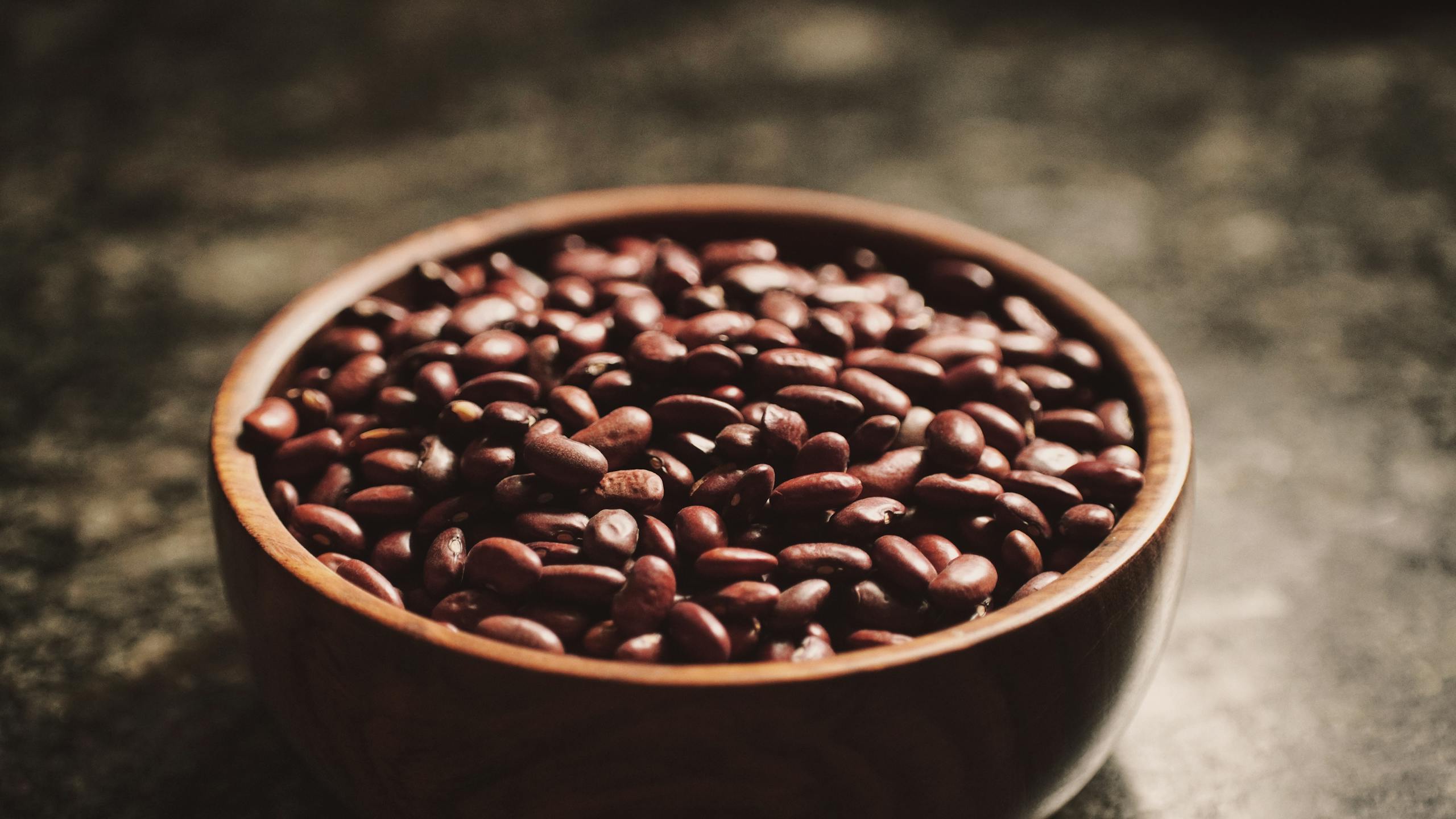 High-quality close-up of a bowl filled with kidney beans on a wooden table.
