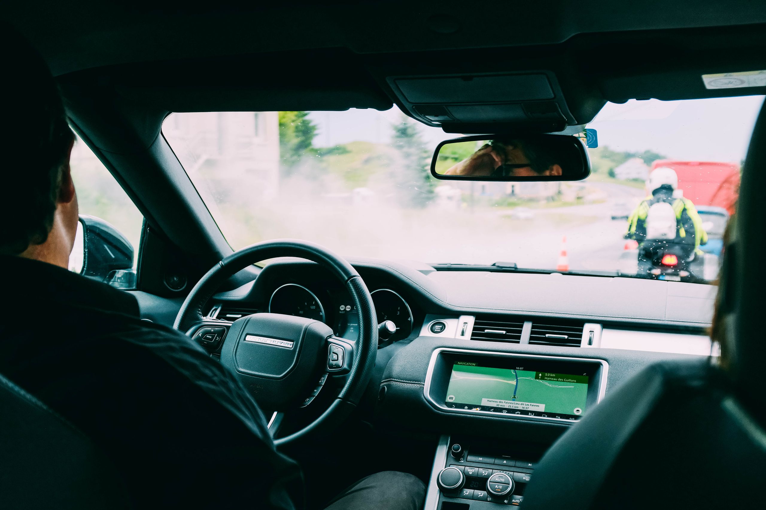 Interior view of a car with GPS navigation and traffic ahead, showcasing urban transportation.