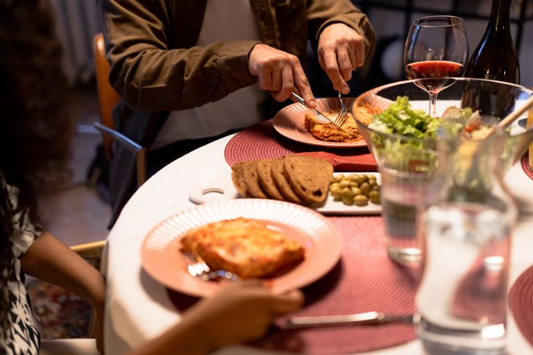 Intimate dinner setting featuring lasagna, salad, and wine on a beautifully set table.